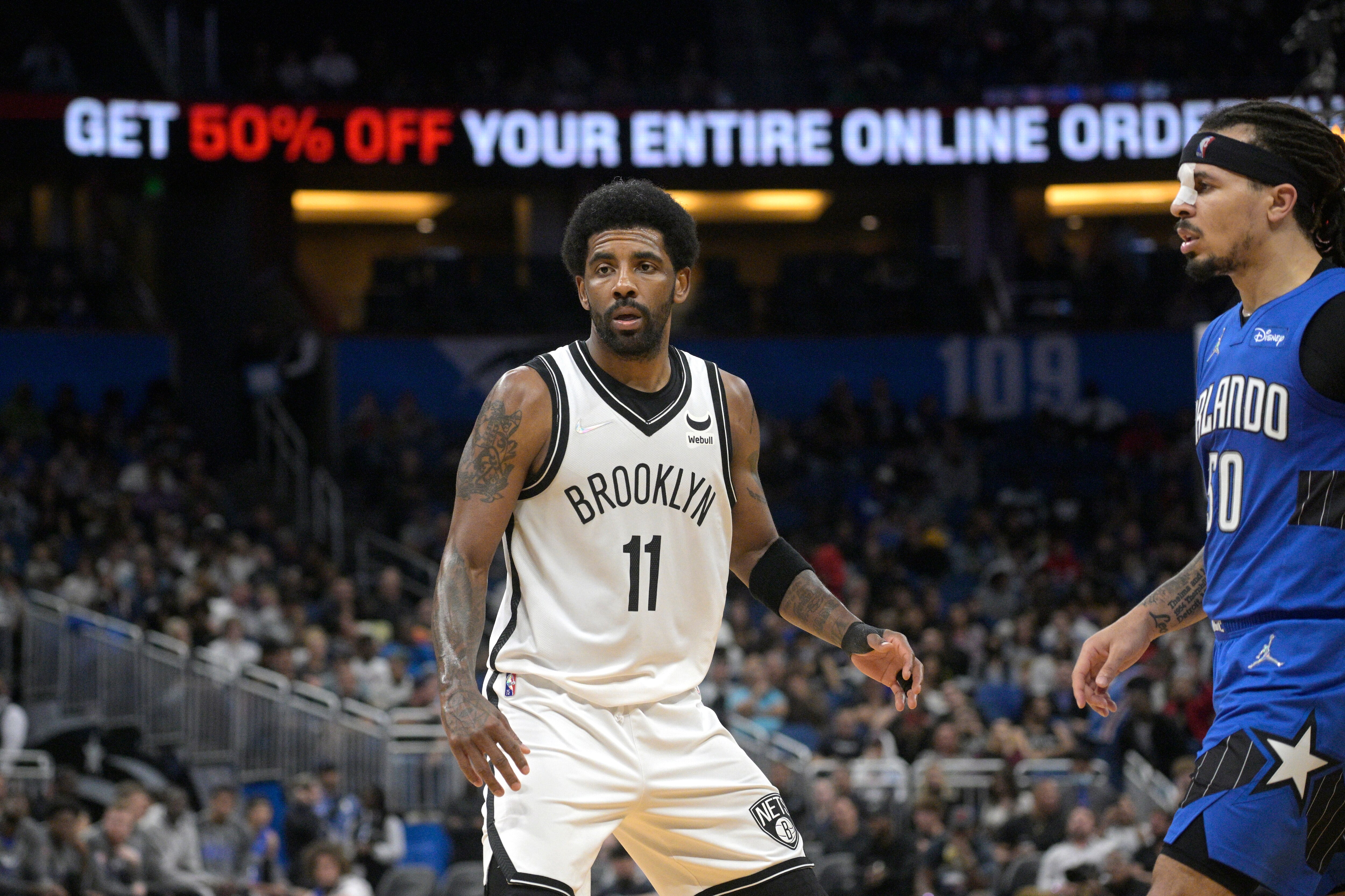 Brooklyn Nets guard Kyrie Irving (11) defends against Orlando Magic guard Cole Anthony (50) during the second half of an NBA basketball game, Tuesday, March 15, 2022, in Orlando, Fla. (AP Photo/Phelan M. Ebenhack)