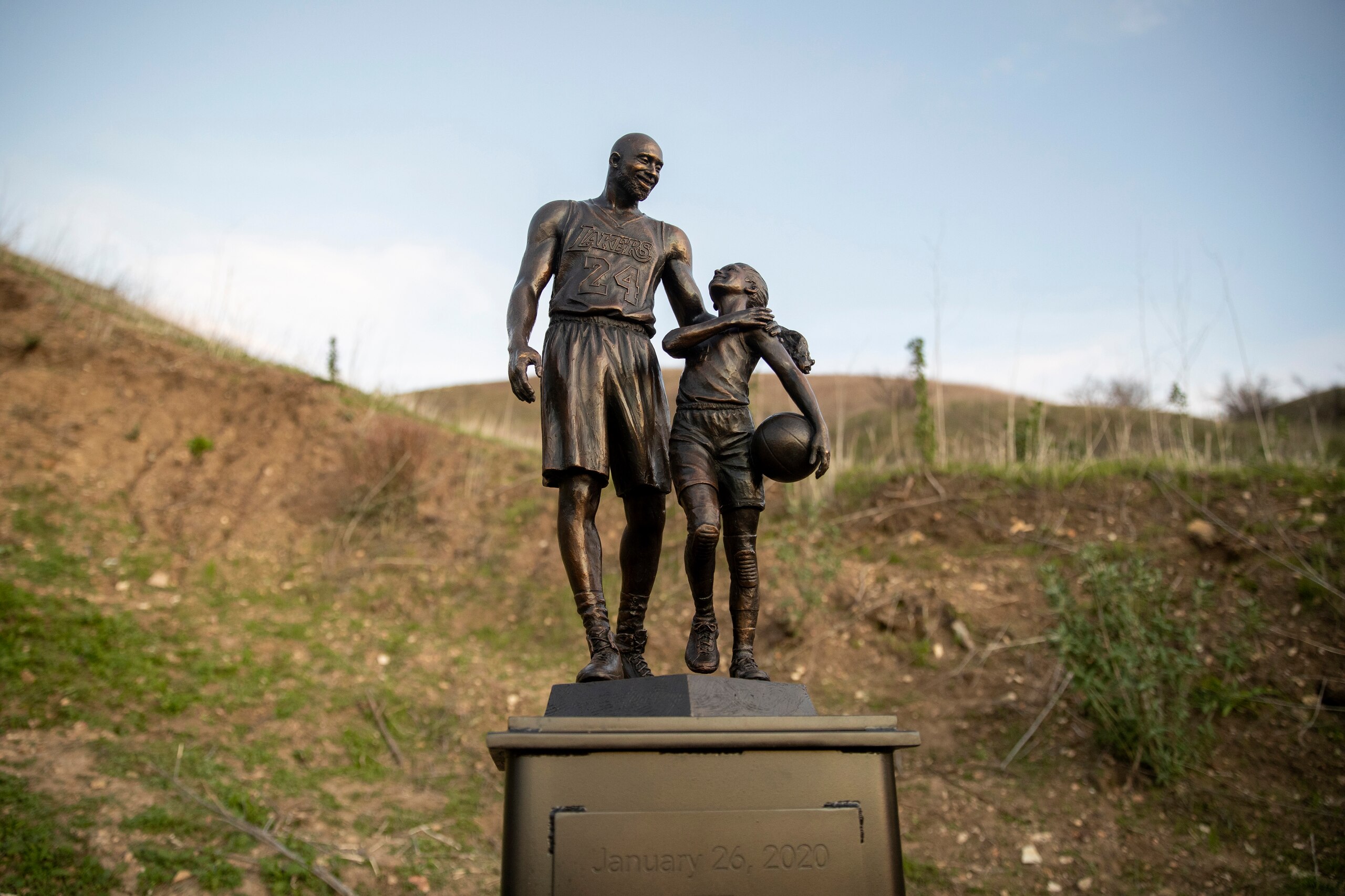 CALABASAS, CA - JANUARY 26: Artist Dan Medina's bronze sculpture depicting Kobe Bryant, daughter Gianna Bryant, and the names of those who died in a helicopter crash in 2020 is seen during a one-day temporary memorial display in Calabasas, California, on January 26, 2022. Retired Los Angeles Lakers star Kobe Bryant died along with his daughter Gianna in a helicopter crash that killed nine people on January 26, 2020. The sculpture was temporarily placed at the site of the crash. (Photo by Josh Lefkowitz/Getty Images)
