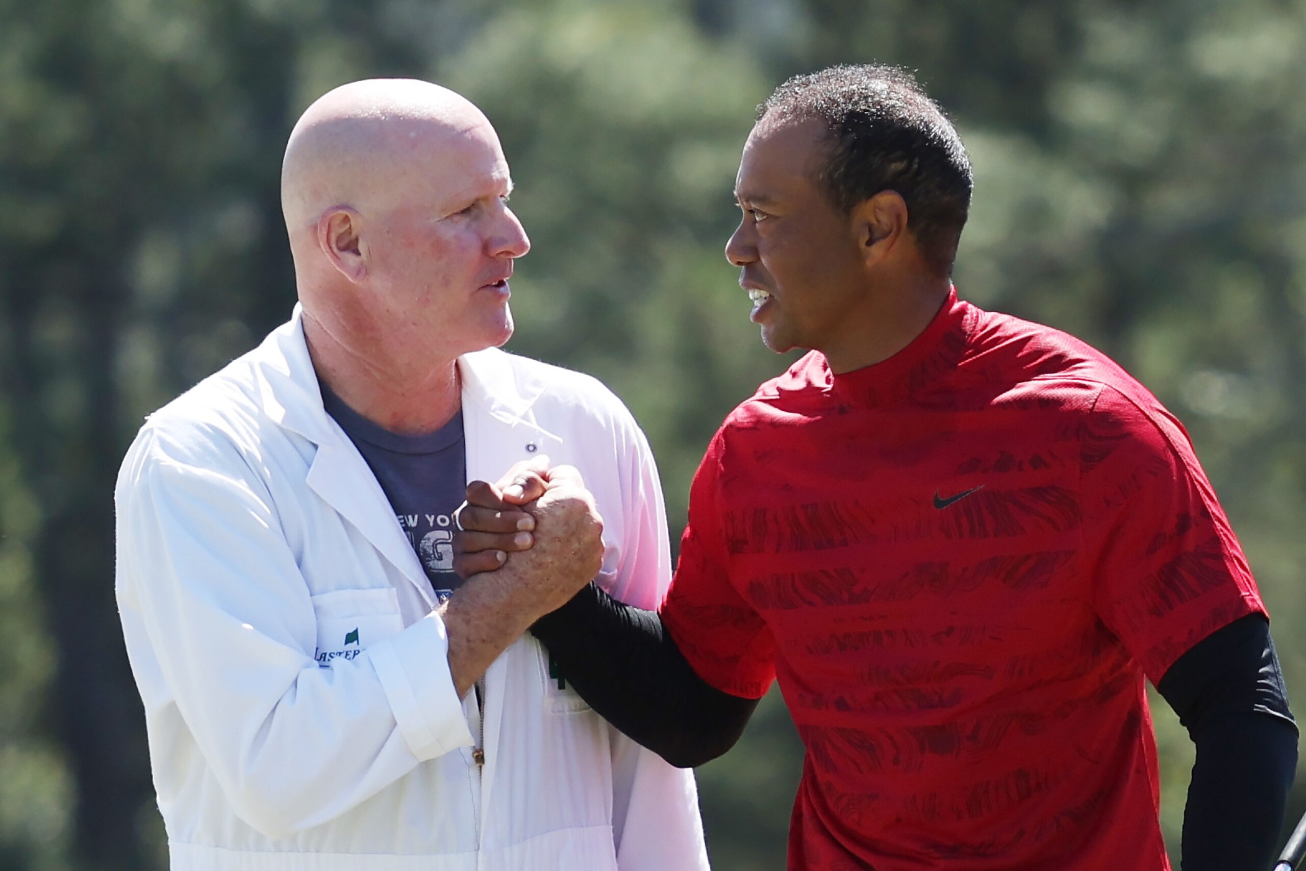 AUGUSTA, GEORGIA - APRIL 10: Tiger Woods and caddie Joe LaCava shake hands on the 18th green after finishing their round during the final round of the Masters at Augusta National Golf Club on April 10, 2022 in Augusta, Georgia. (Photo by Gregory Shamus/Getty Images)