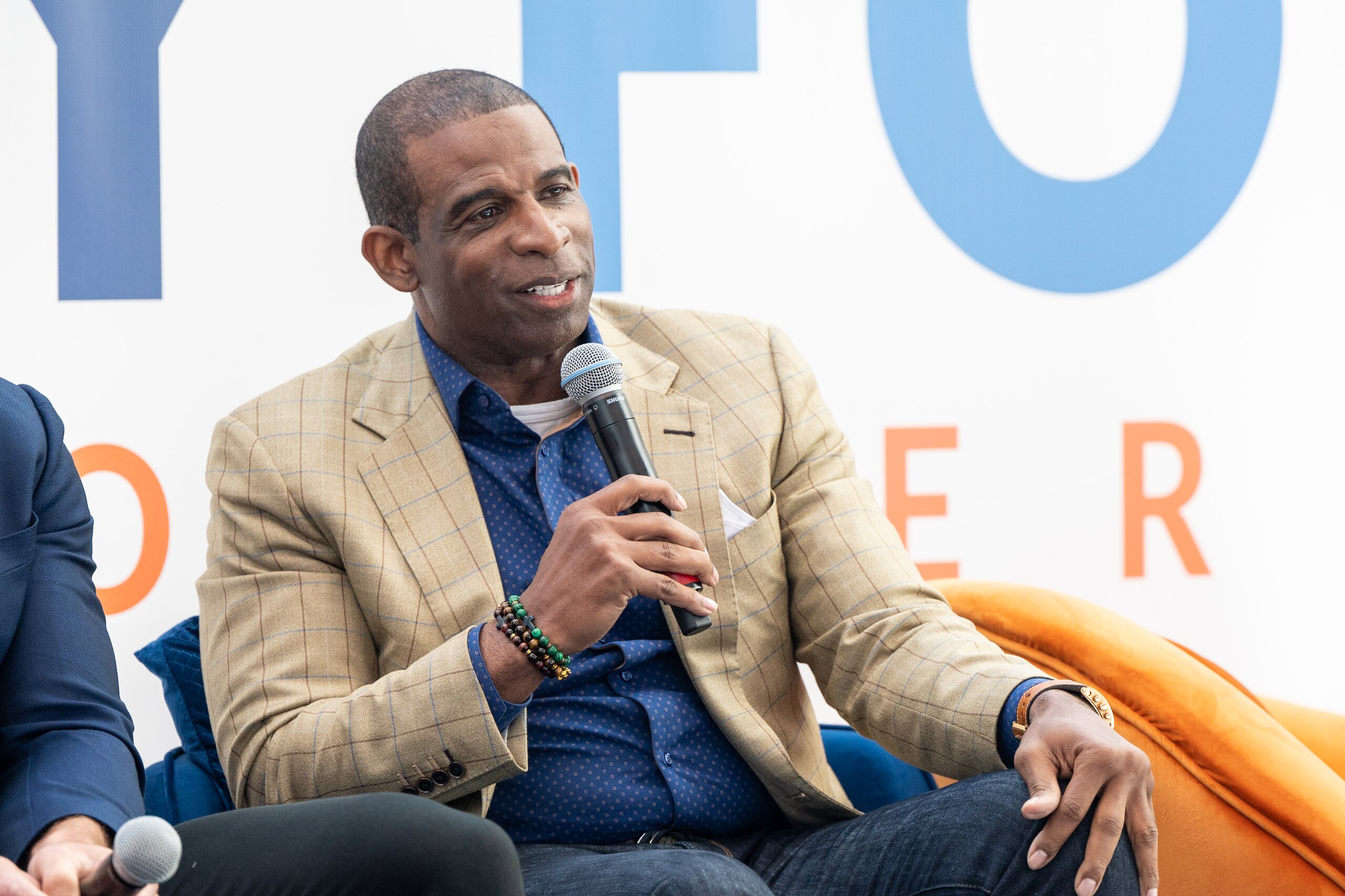 ATLANTA, GEORGIA - MARCH 04: Deion Sanders speaks on stage during the 2022 International Poverty Forum at Porsche Cars North America on March 04, 2022 in Atlanta, Georgia. (Photo by Derek White/Getty Images)