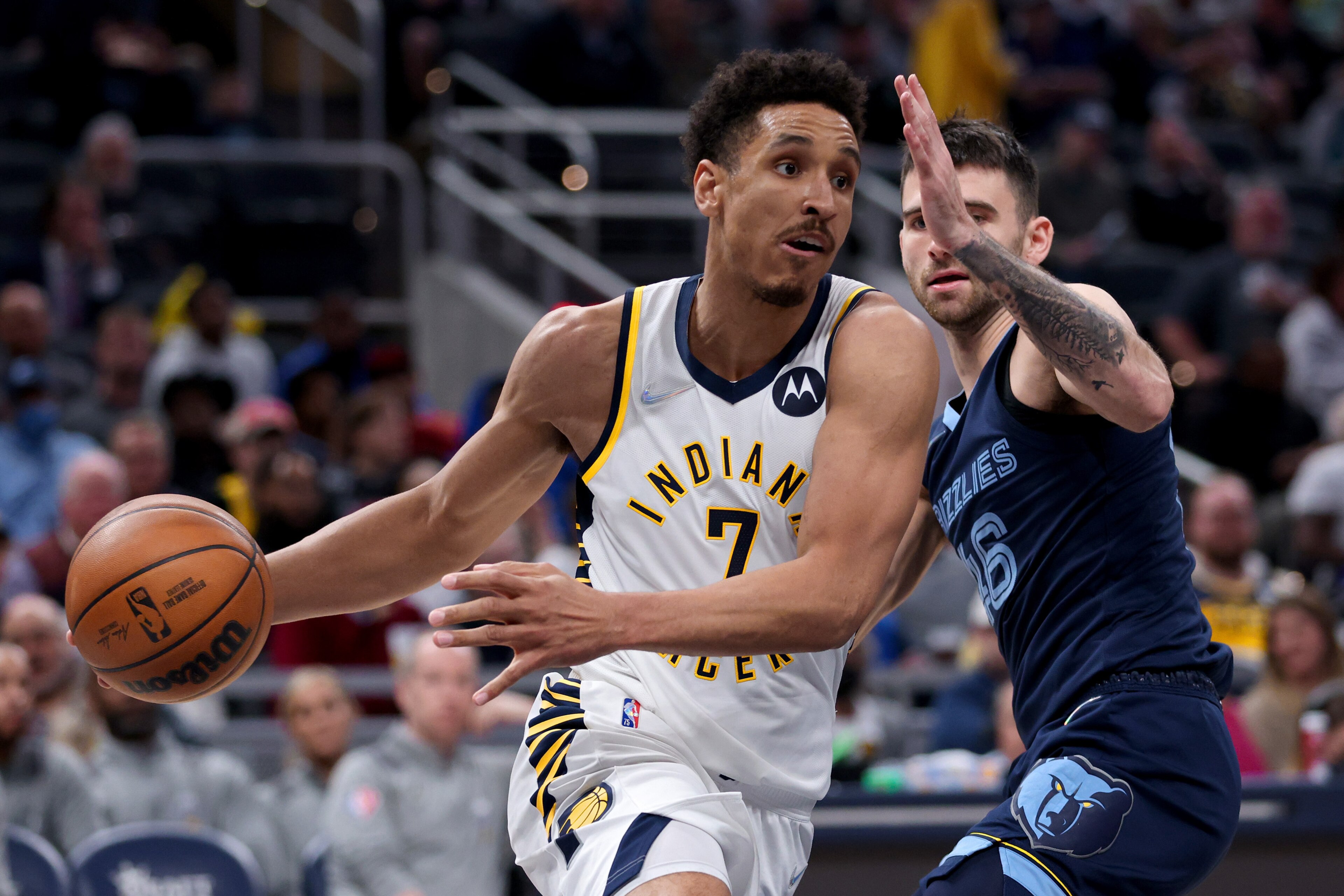 INDIANAPOLIS, INDIANA - MARCH 15: Malcolm Brogdon #7 of the Indiana Pacers dribbles the ball while being guarded by John Konchar #46 of the Memphis Grizzlies in the fourth quarter at Gainbridge Fieldhouse on March 15, 2022 in Indianapolis, Indiana. NOTE TO USER: User expressly acknowledges and agrees that, by downloading and or using this Photograph, user is consenting to the terms and conditions of the Getty Images License Agreement. (Photo by Dylan Buell/Getty Images)