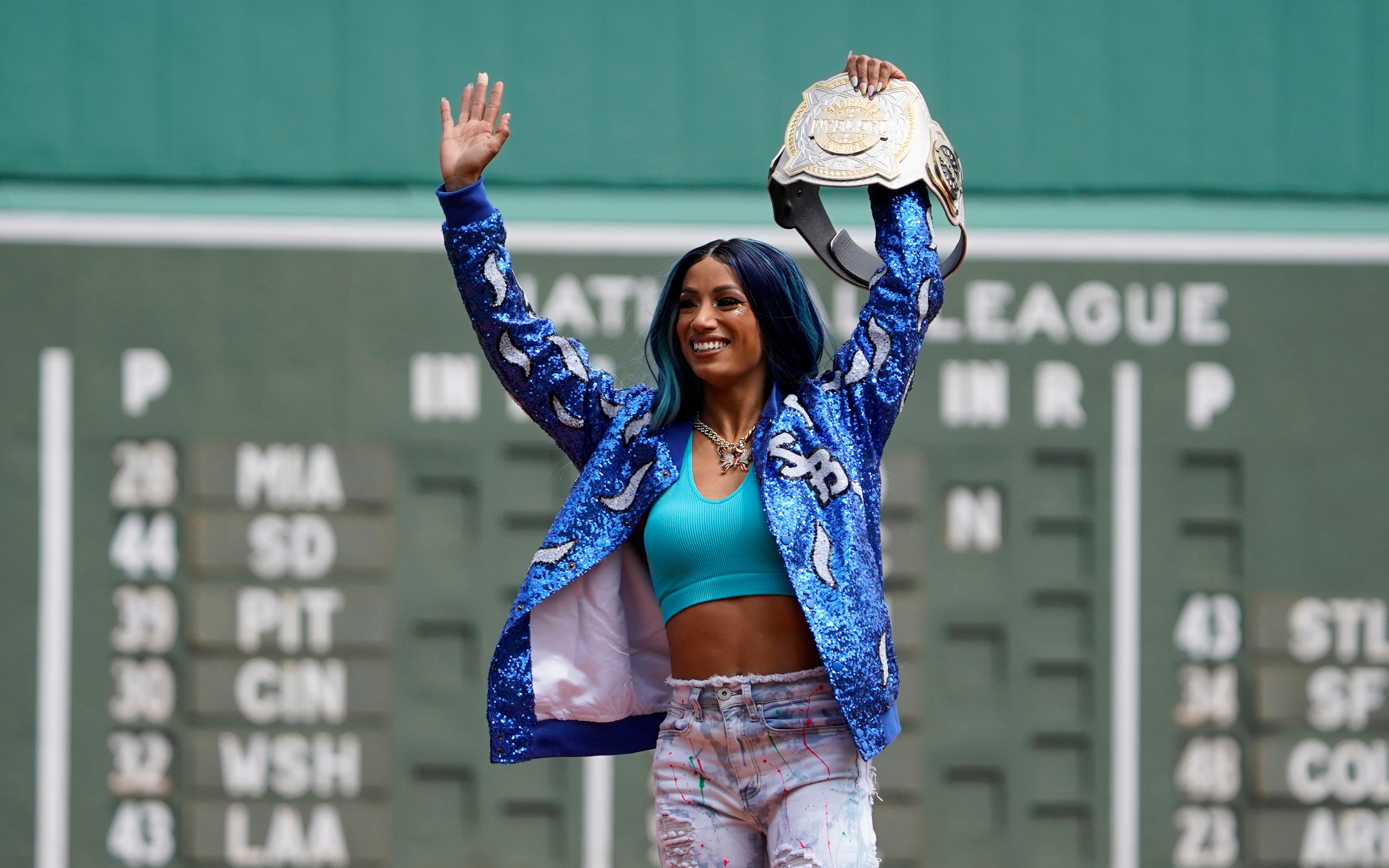WWE wrestler Sasha Banks reacts before throwing out the first pitch before the start of baseball game between the Boston Red Sox and the Chicago White Sox at Fenway Park, Sunday, May 8, 2022, in Boston. (AP Photo/Mary Schwalm)