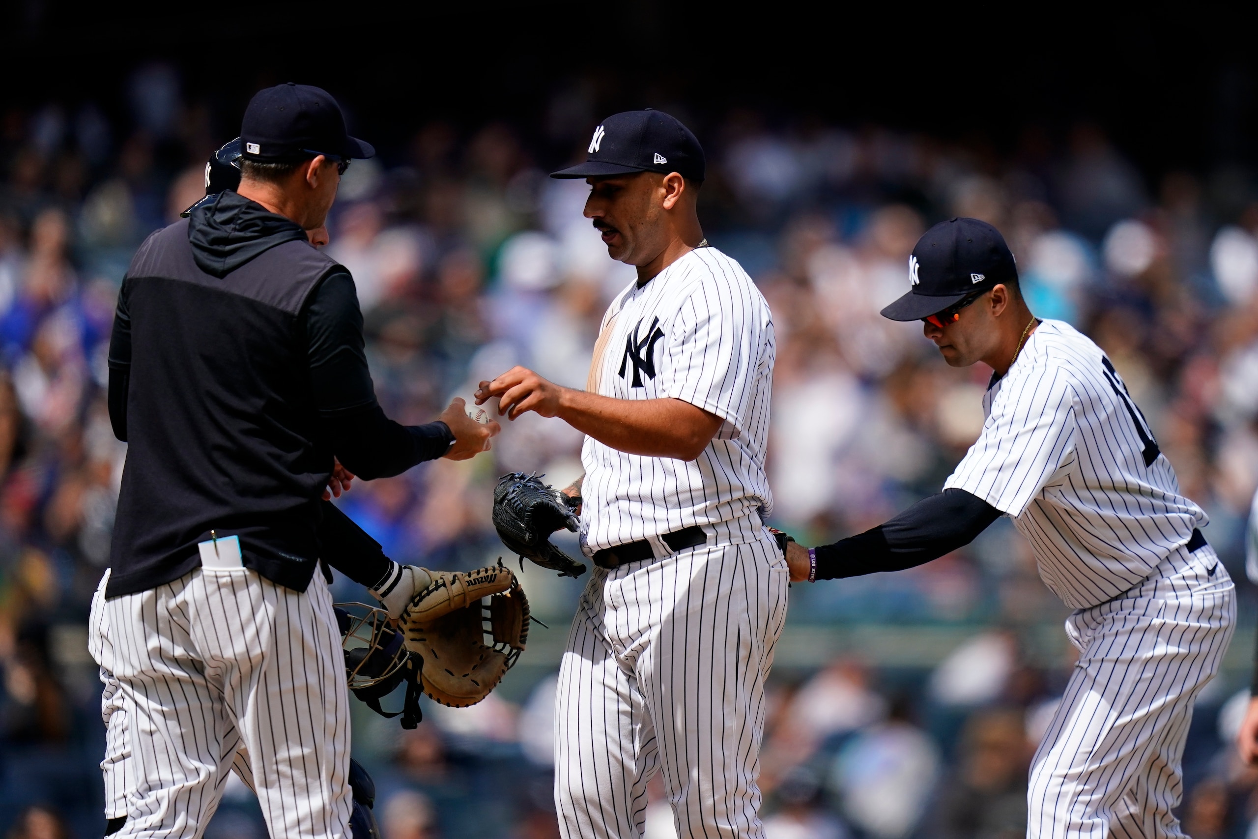 New York Yankees manager Aaron Boone, left, takes the ball from starting pitcher Nestor Cortes, center, as he leaves during the seventh inning of a baseball game against the Cleveland Guardians Saturday, April 23, 2022, in New York. (AP Photo/Frank Franklin II)