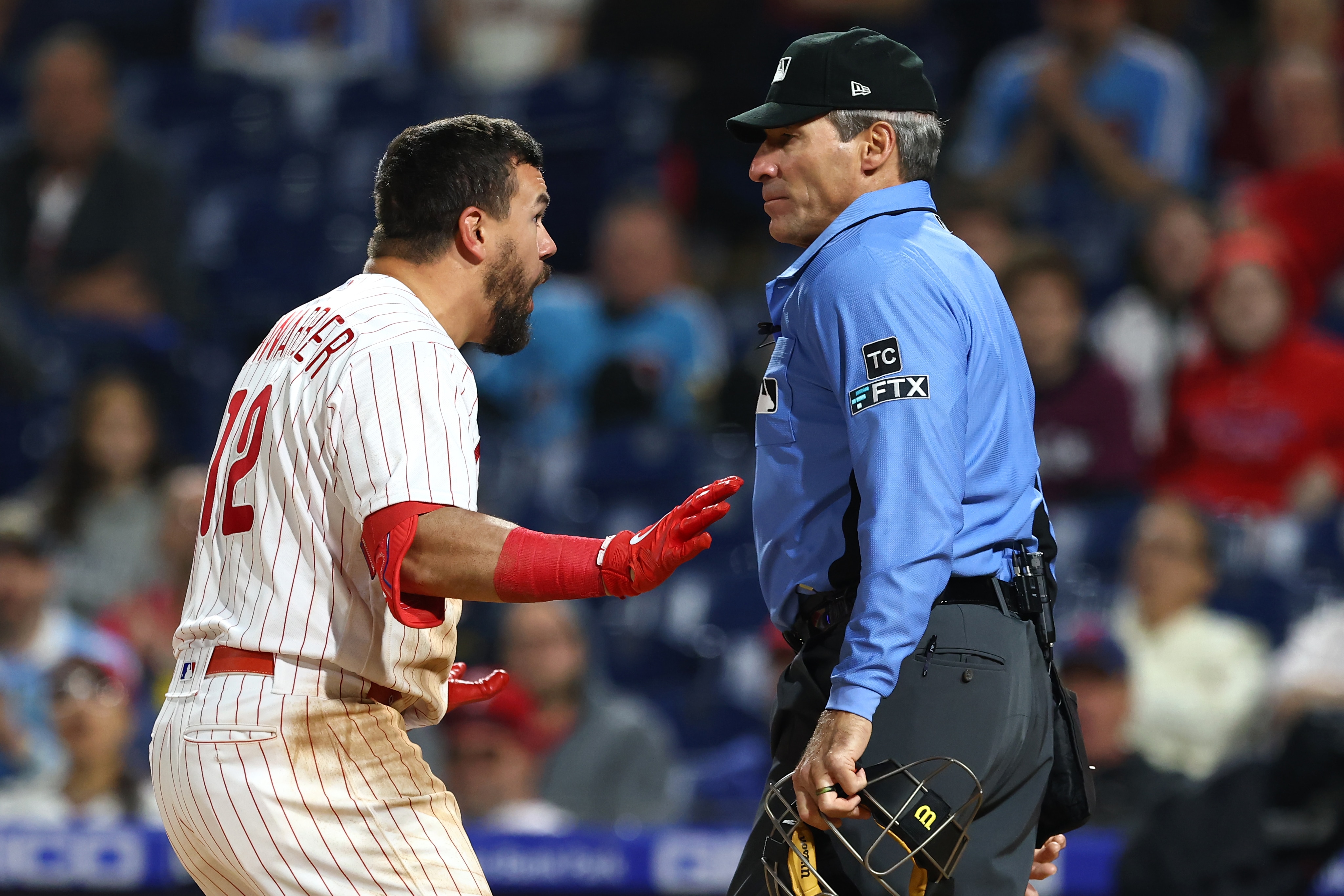 PHILADELPHIA, PA - APRIL 24: Kyle Schwarber #12 of the Philadelphia Phillies argues with home plate umpire Angel Hernandez after being called out on strikes during the ninth inning against the Milwaukee Brewers at Citizens Bank Park on April 24, 2022 in Philadelphia, Pennsylvania. The Brewers defeated the Phillies 1-0. (Photo by Rich Schultz/Getty Images)