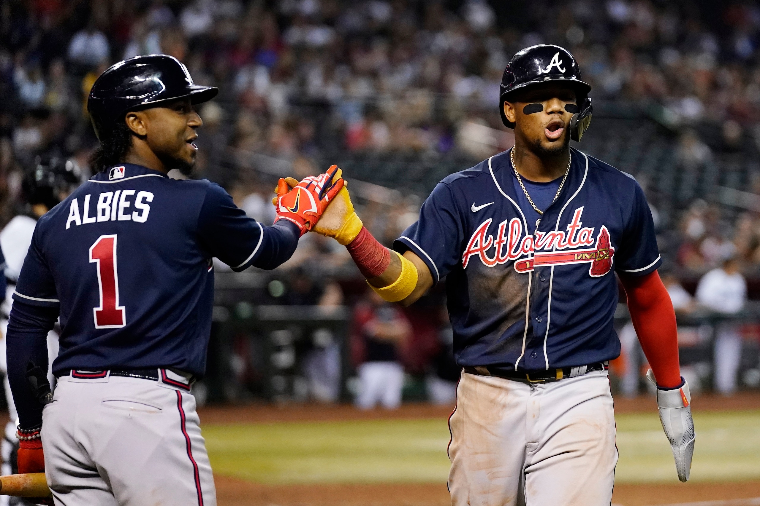 Atlanta Braves' Ronald Acuna Jr., right, celebrates with Ozzie Albies (1) after Acuna scored against the Arizona Diamondbacks during the fifth inning of a baseball game Tuesday, May 31, 2022, in Phoenix. (AP Photo/Ross D. Franklin)