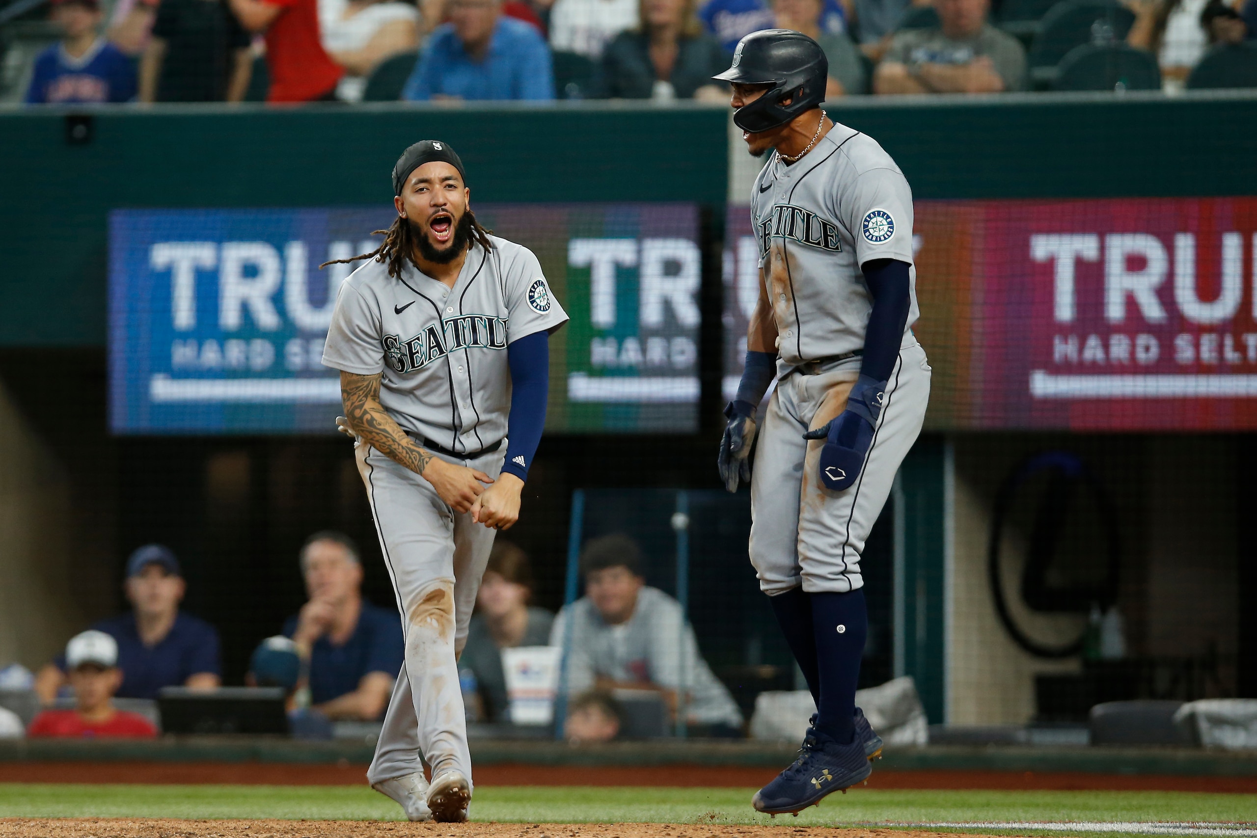 ARLINGTON, TEXAS - JUNE 05: J.P. Crawford #3 of the Seattle Mariners and Julio Rodriguez #44 react after scoring runs in the ninth inning against the Texas Rangers at Globe Life Field on June 05, 2022 in Arlington, Texas. (Photo by Tim Heitman/Getty Images)