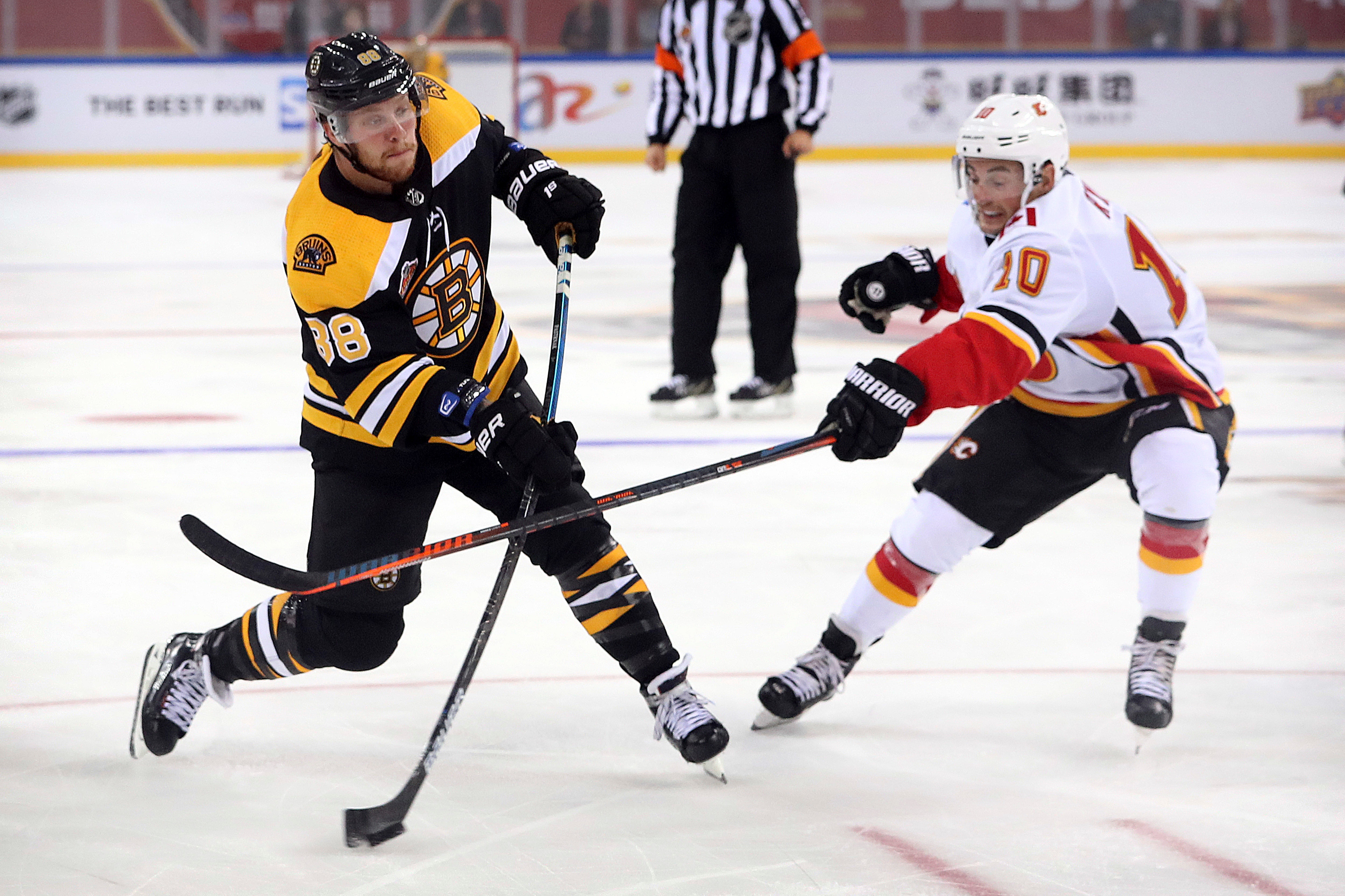David Pastrnak (88) of the Boston Bruins takes a shot on goal past Derek Ryan (10) of the Calgary Flames during the second period of their 2018 NHL China Games hockey game in Beijing, China, Wednesday, Sept. 19, 2018. Boston beat Calgary, 3-1. (AP Photo/Mark Schiefelbein)