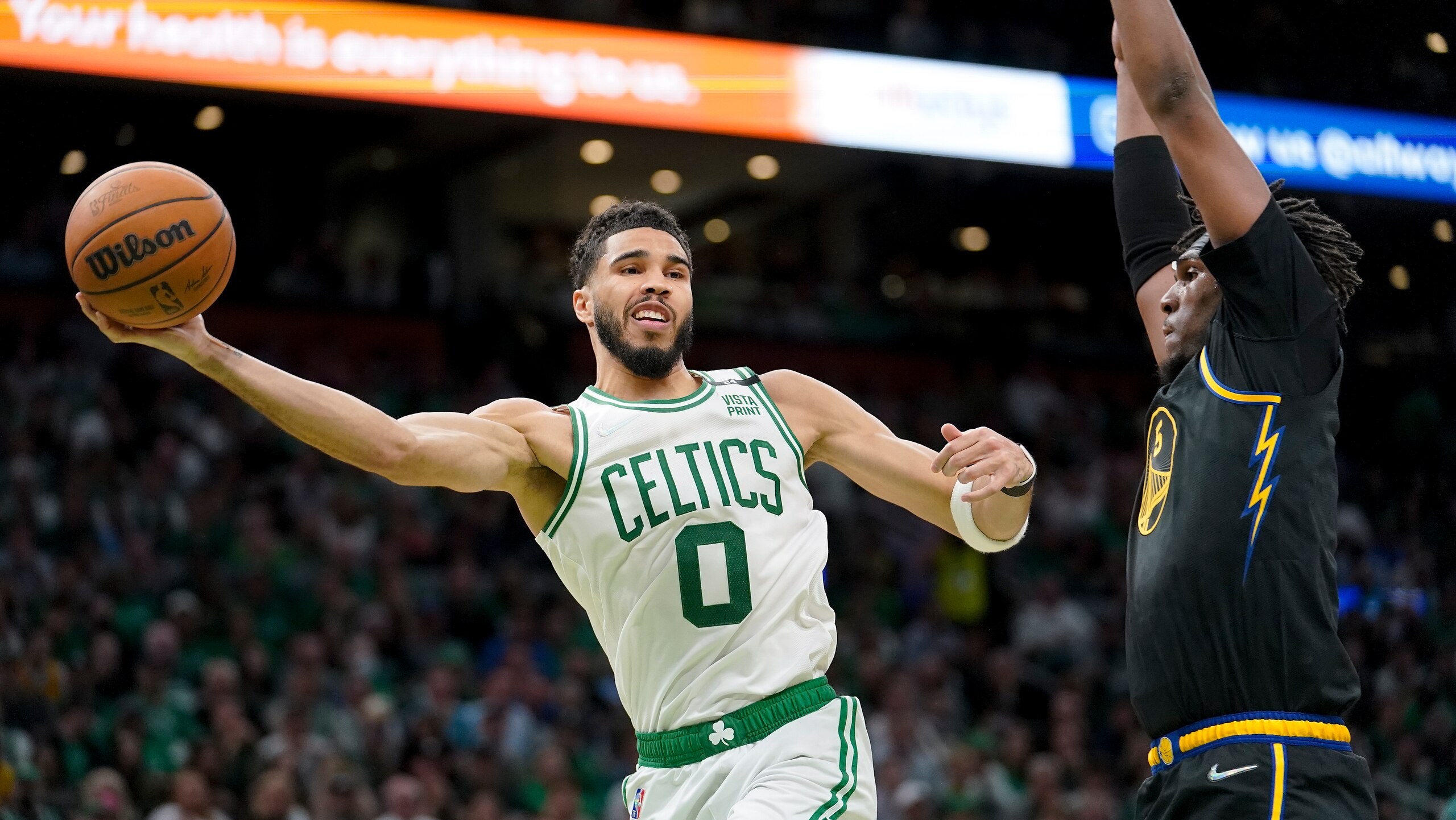 Boston Celtics forward Jayson Tatum (0) passes against Golden State Warriors center Kevon Looney (5) during the first quarter of Game 3 of basketball's NBA Finals, Wednesday, June 8, 2022, in Boston. (AP Photo/Steven Senne)