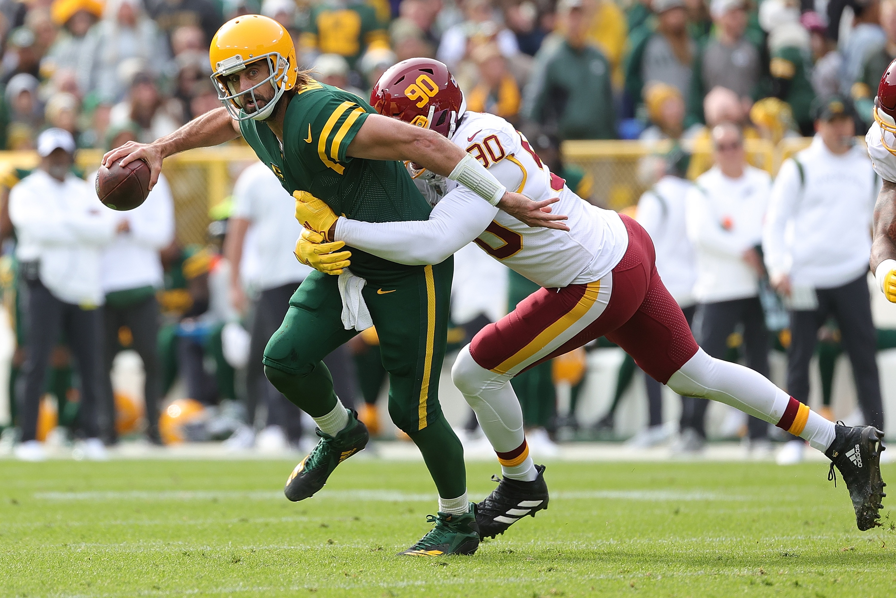 GREEN BAY, WISCONSIN - OCTOBER 24: Aaron Rodgers #12 of the Green Bay Packers is pressured by Montez Sweat #90 of the Washington Football Team during a game at Lambeau Field on October 24, 2021 in Green Bay, Wisconsin. (Photo by Stacy Revere/Getty Images)