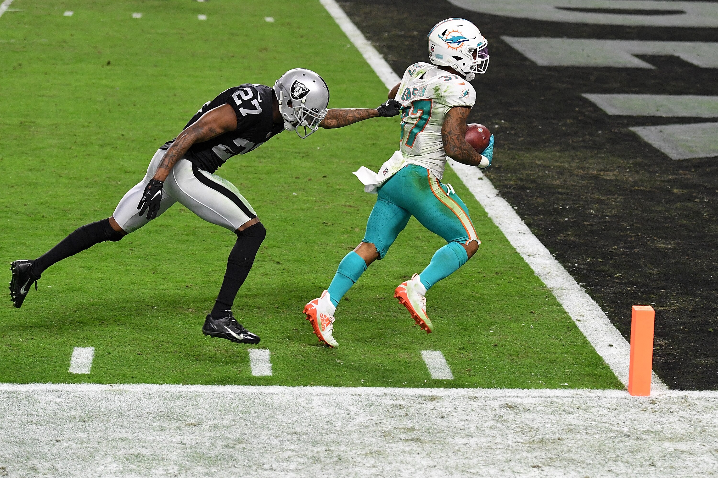 LAS VEGAS, NEVADA - DECEMBER 26:  Myles Gaskin #37 of the Miami Dolphins scores a touchdown in front of Trayvon Mullen Jr. #27 of the Las Vegas Raiders to take the lead in the fourth quarter of a game at Allegiant Stadium on December 26, 2020 in Las Vegas, Nevada. (Photo by Ethan Miller/Getty Images)