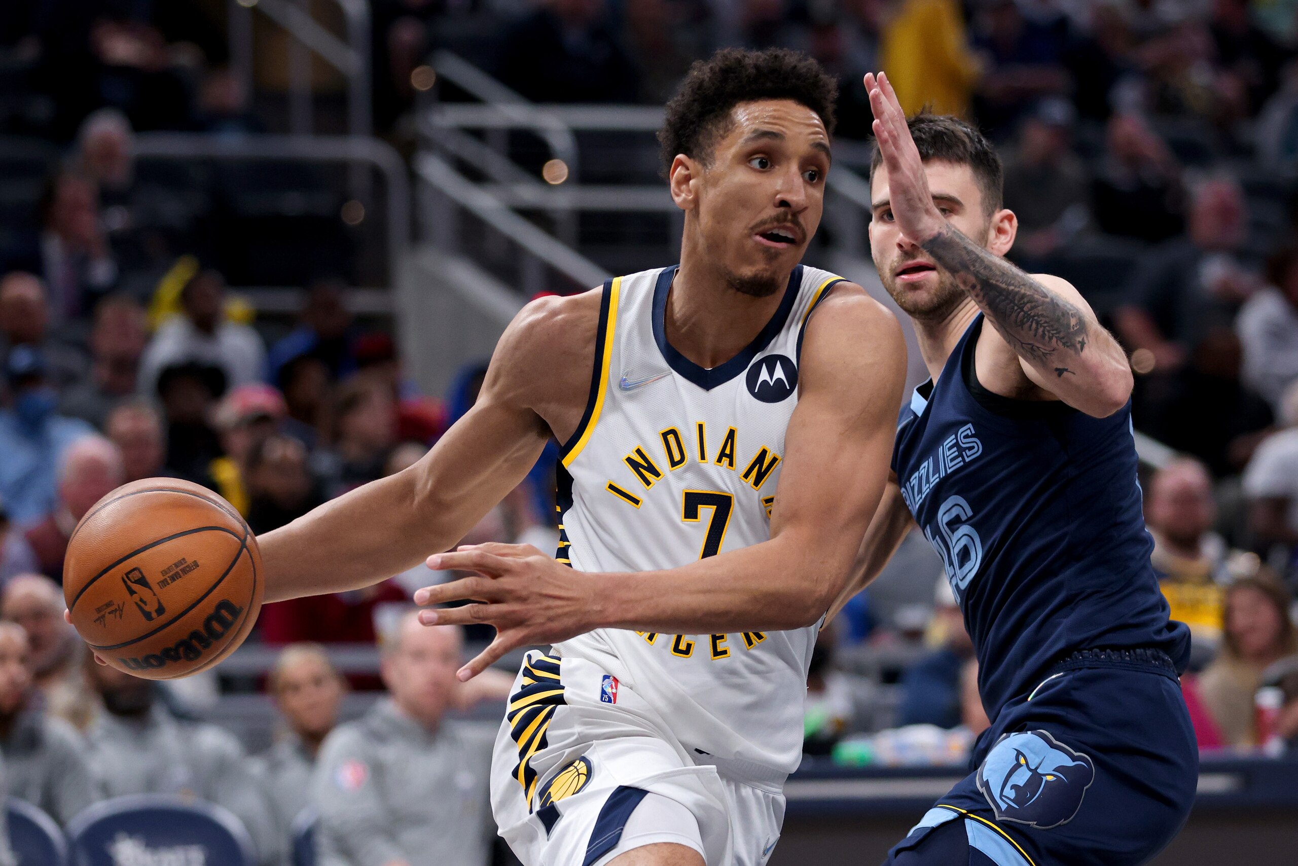 INDIANAPOLIS, INDIANA - MARCH 15: Malcolm Brogdon #7 of the Indiana Pacers dribbles the ball while being guarded by John Konchar #46 of the Memphis Grizzlies in the fourth quarter at Gainbridge Fieldhouse on March 15, 2022 in Indianapolis, Indiana. NOTE TO USER: User expressly acknowledges and agrees that, by downloading and or using this Photograph, user is consenting to the terms and conditions of the Getty Images License Agreement. (Photo by Dylan Buell/Getty Images)