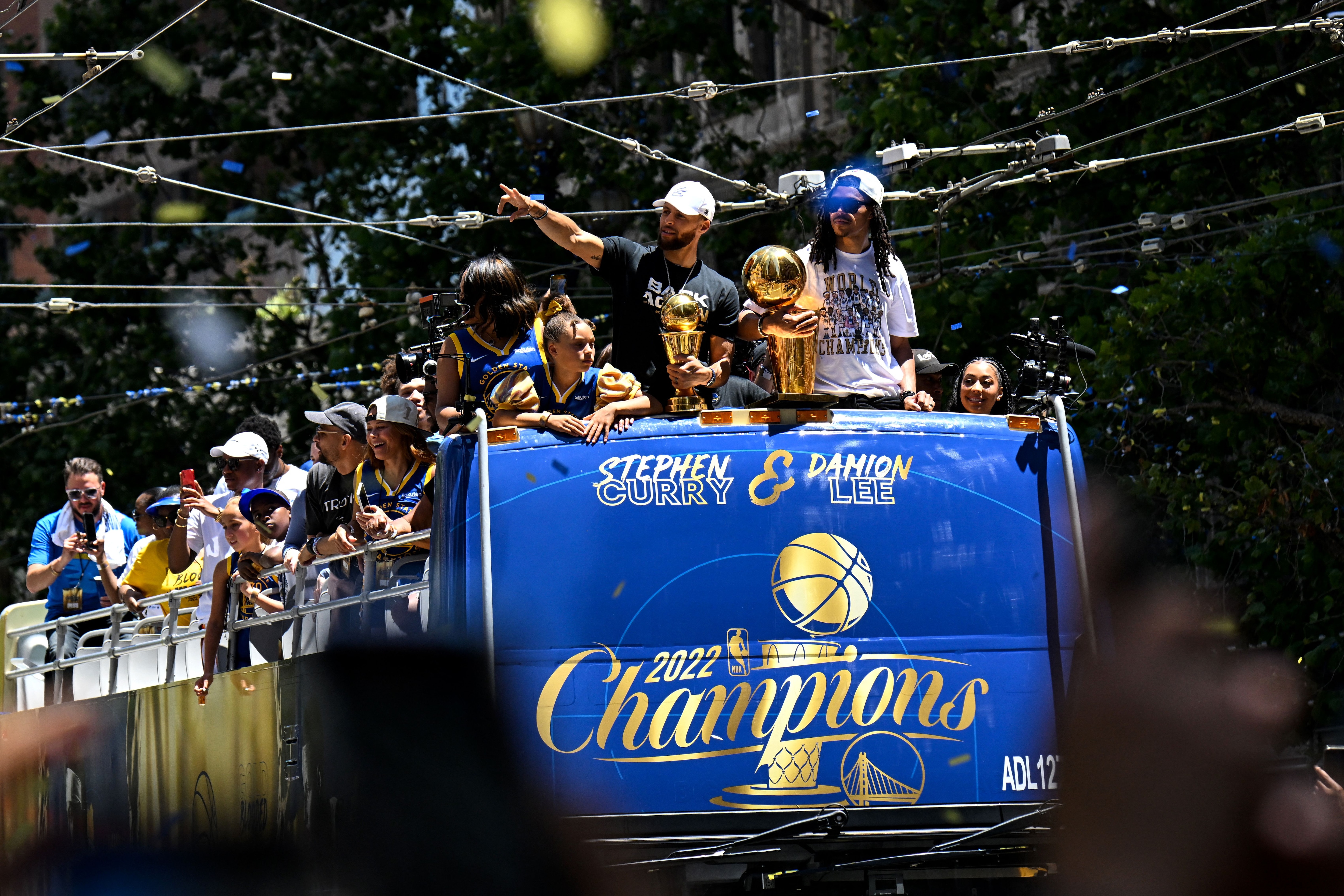 US basketball player Stephen Curry (L) holds the MVP trophy alongside teammate Damion Lee (R) as they celebrate from a double decker bus during the Golden State Warriors NBA Championship victory parade along Market Street in San Francisco, California on June 20, 2022. (Photo by Patrick T. FALLON / AFP) (Photo by PATRICK T. FALLON/AFP via Getty Images)