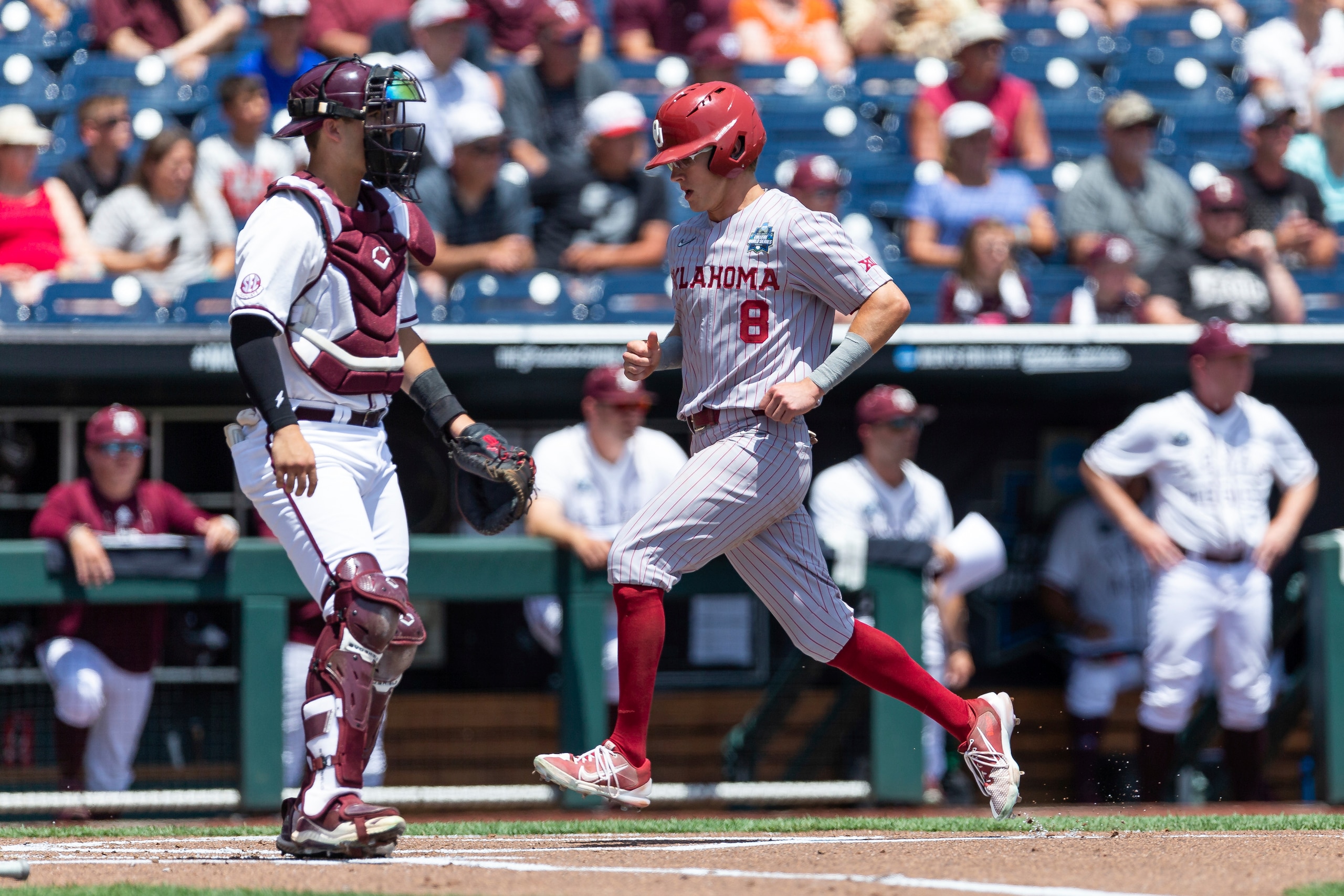 Oklahoma outfielder John Spikerman (8) scores a run against Texas A&M in the first inning during an NCAA College World Series baseball game Friday, June 17, 2022, in Omaha, Neb. (AP Photo/John Peterson)
