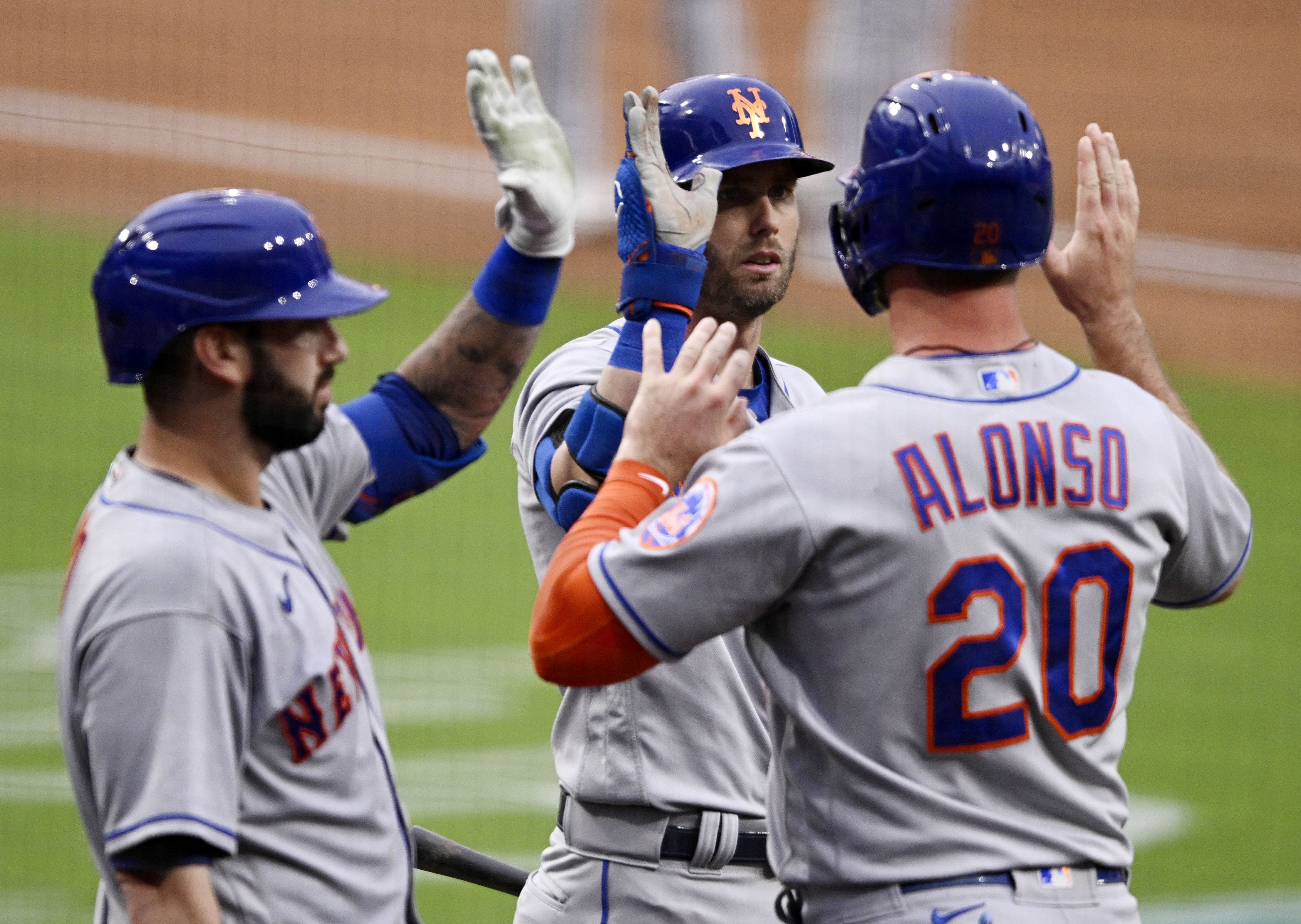SAN DIEGO, CA - JUNE 6: Pete Alonso #20 of the New York Mets (R) is congratulated by Jeff McNeil #1 and Tomas Nido #3 after scoring during the first inning of a baseball game against the San Diego Padres on June 6, 2022 at Petco Park in San Diego, California. (Photo by Denis Poroy/Getty Images)
