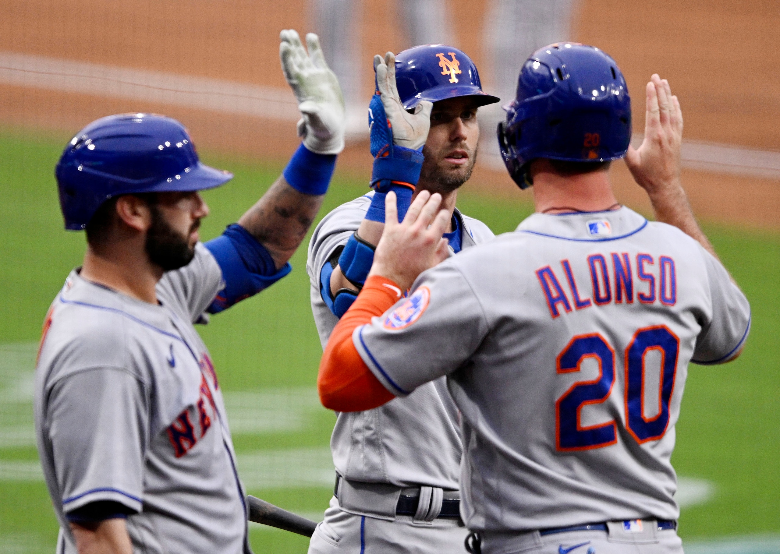 SAN DIEGO, CA - JUNE 6: Pete Alonso #20 of the New York Mets (R) is congratulated by Jeff McNeil #1 and Tomas Nido #3 after scoring during the first inning of a baseball game against the San Diego Padres on June 6, 2022 at Petco Park in San Diego, California. (Photo by Denis Poroy/Getty Images)