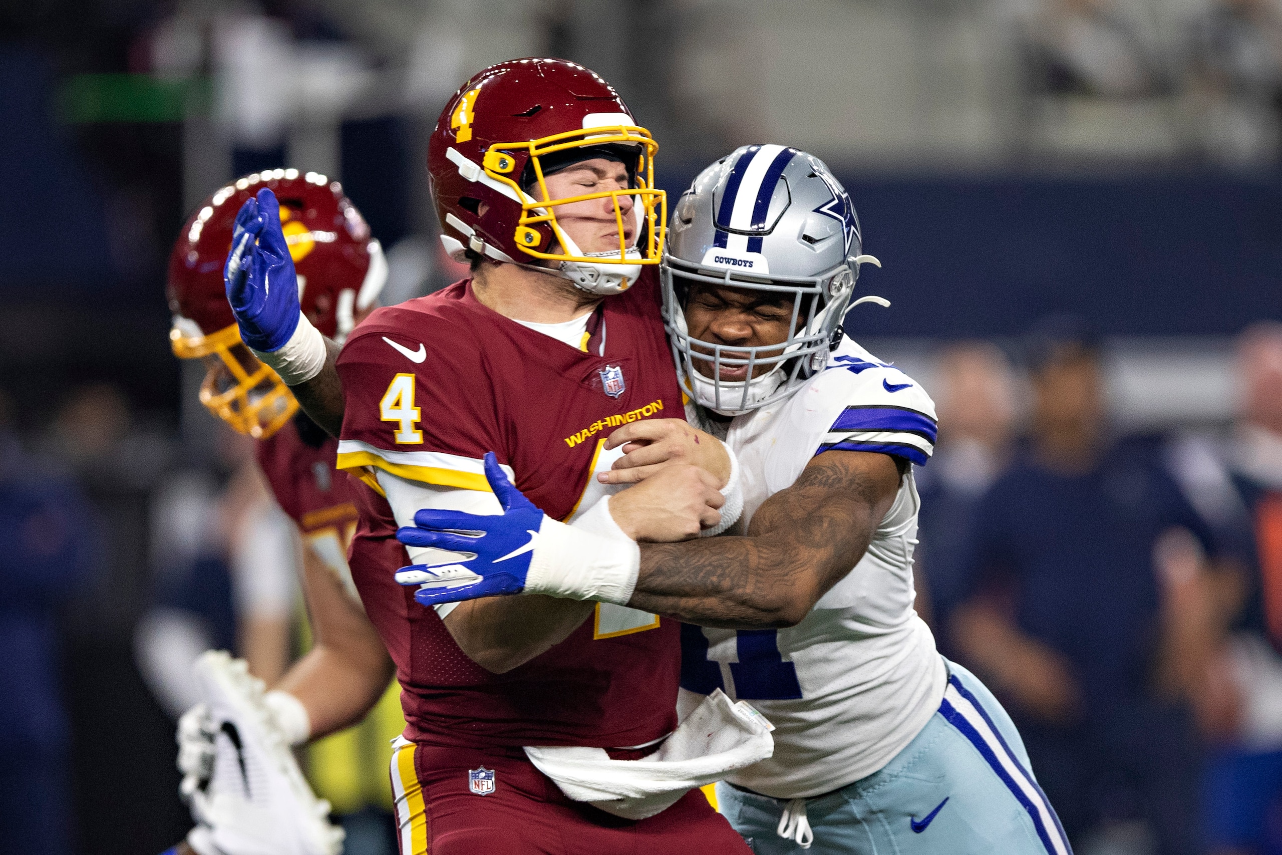 ARLINGTON, TEXAS - DECEMBER 26:  Taylor Heinicke #4 of the Washington Football Team is hit after throwing a pass by Micah Parsons #11 of the Dallas Cowboys at AT&T Stadium on December 26, 2021 in Arlington, Texas.  The Cowboys defeated the Football Team 56-14.  (Photo by Wesley Hitt/Getty Images)