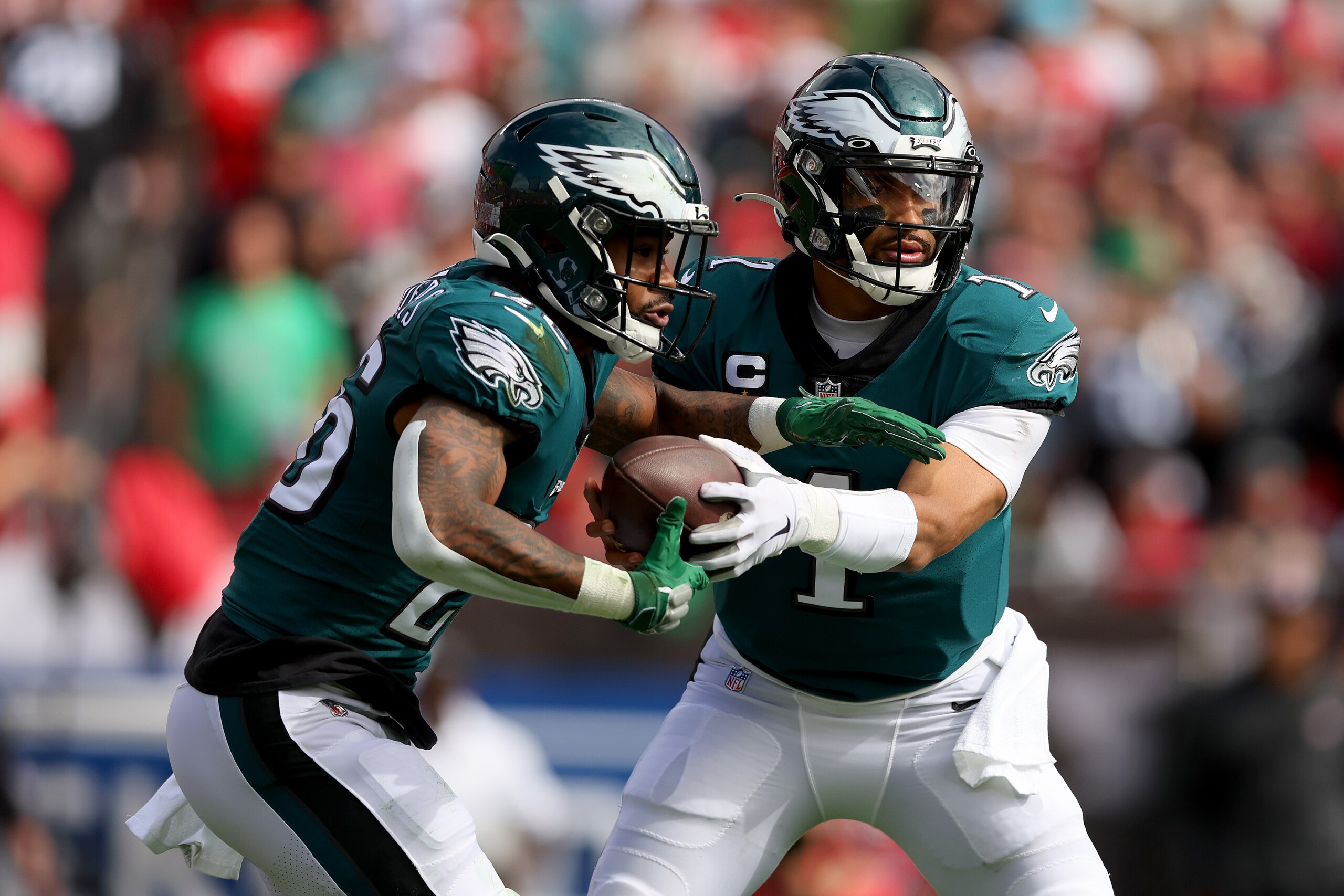 TAMPA, FLORIDA - JANUARY 16: Jalen Hurts #1 of the Philadelphia Eagles hands the ball off to Miles Sanders #26 against the Tampa Bay Buccaneers during the first quarter in the NFC Wild Card Playoff game at Raymond James Stadium on January 16, 2022 in Tampa, Florida. (Photo by Michael Reaves/Getty Images)