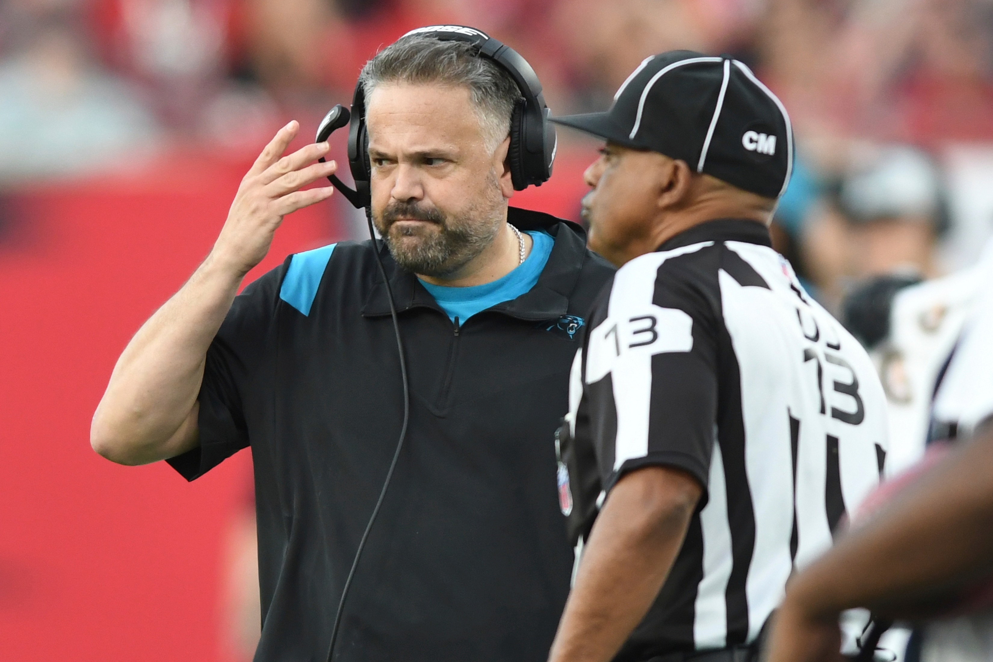 Carolina Panthers head coach Matt Rhule talks to down judge Patrick Turner (13) during the first half of an NFL football game against the Tampa Bay Buccaneers Sunday, Jan. 9, 2022, in Tampa, Fla. (AP Photo/Jason Behnken)