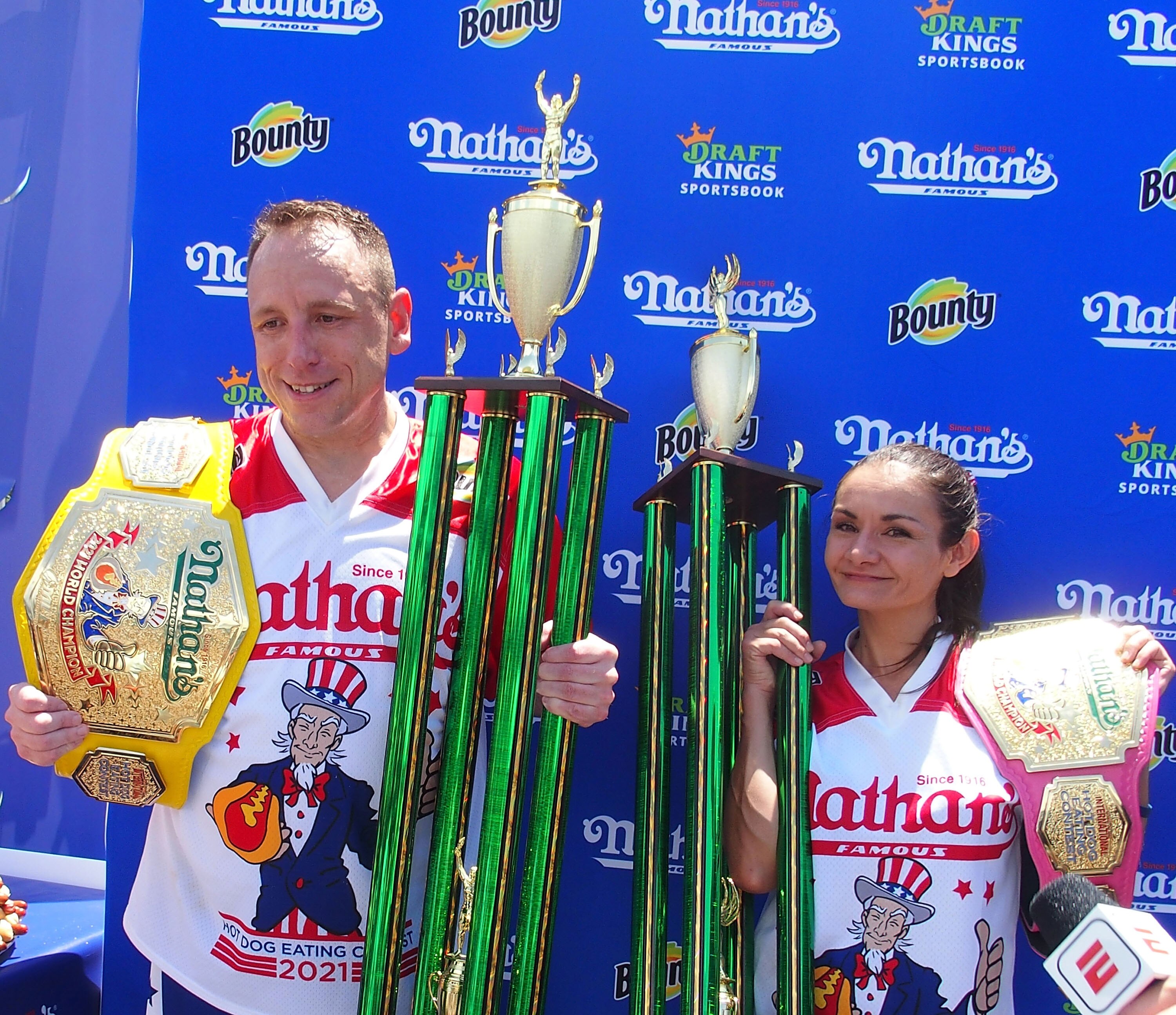 NEW YORK, NY - JULY 04:  Winners Joey Chestnut and Michelle Lesco pose with their championship belts and trophies at the 2021 Nathan's Famous International Hot Dog Eating Contest at Coney Island on July 4, 2021 in New York City.  (Photo by Bobby Bank/WireImage)