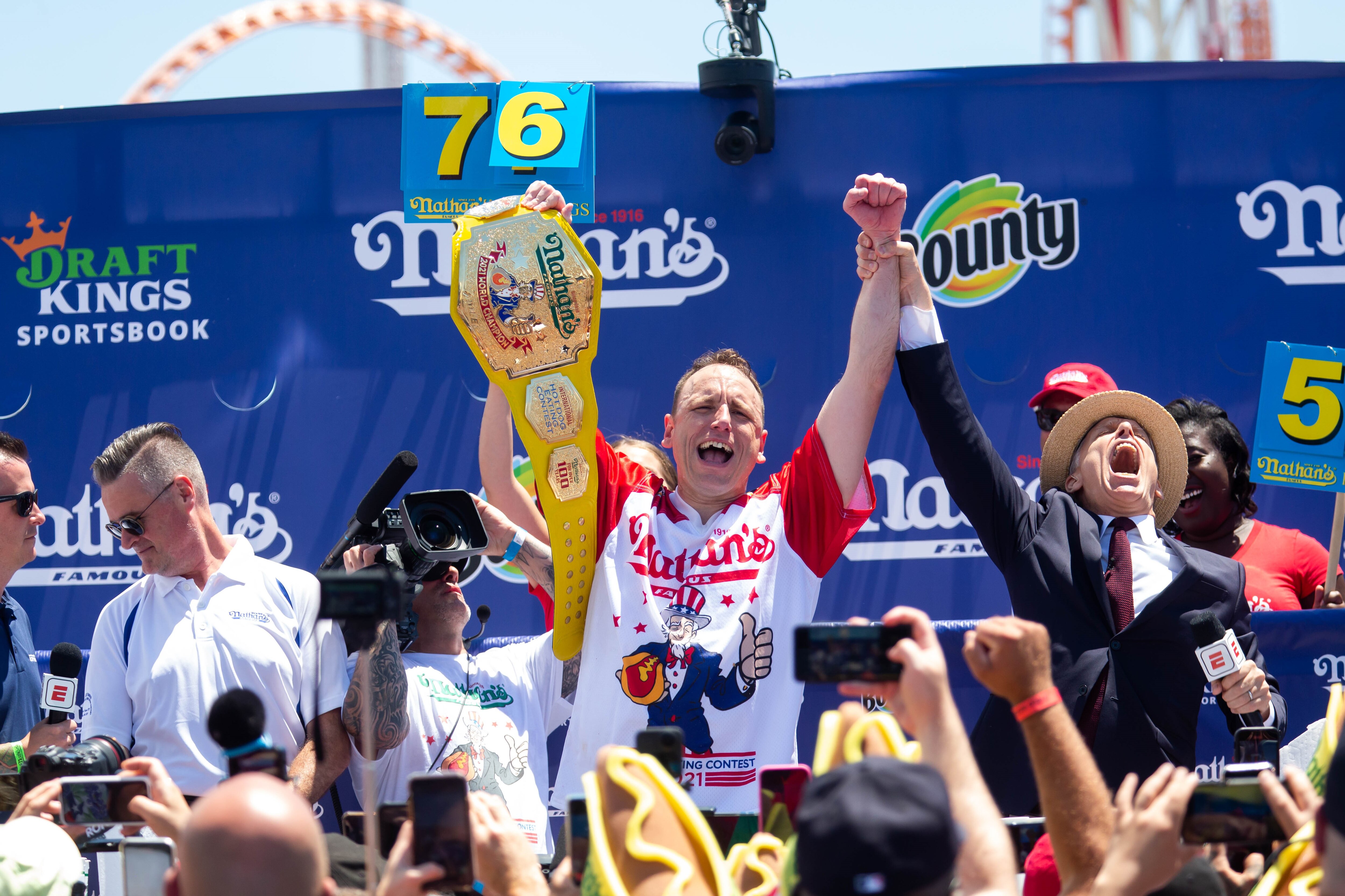 Joey Chestnut C celebrates after defending his men's championship title in a hot dog eating contest in New York, the United States, on July 4, 2021. Defending champion Joey Chestnut broke his own world record Sunday by devouring 76 hot dogs in 10 minutes at the contest. Michelle Lesco won the women's title by eating 30.75 hot dogs in 10 minutes. (Photo by Michael Nagle/Xinhua via Getty Images)
