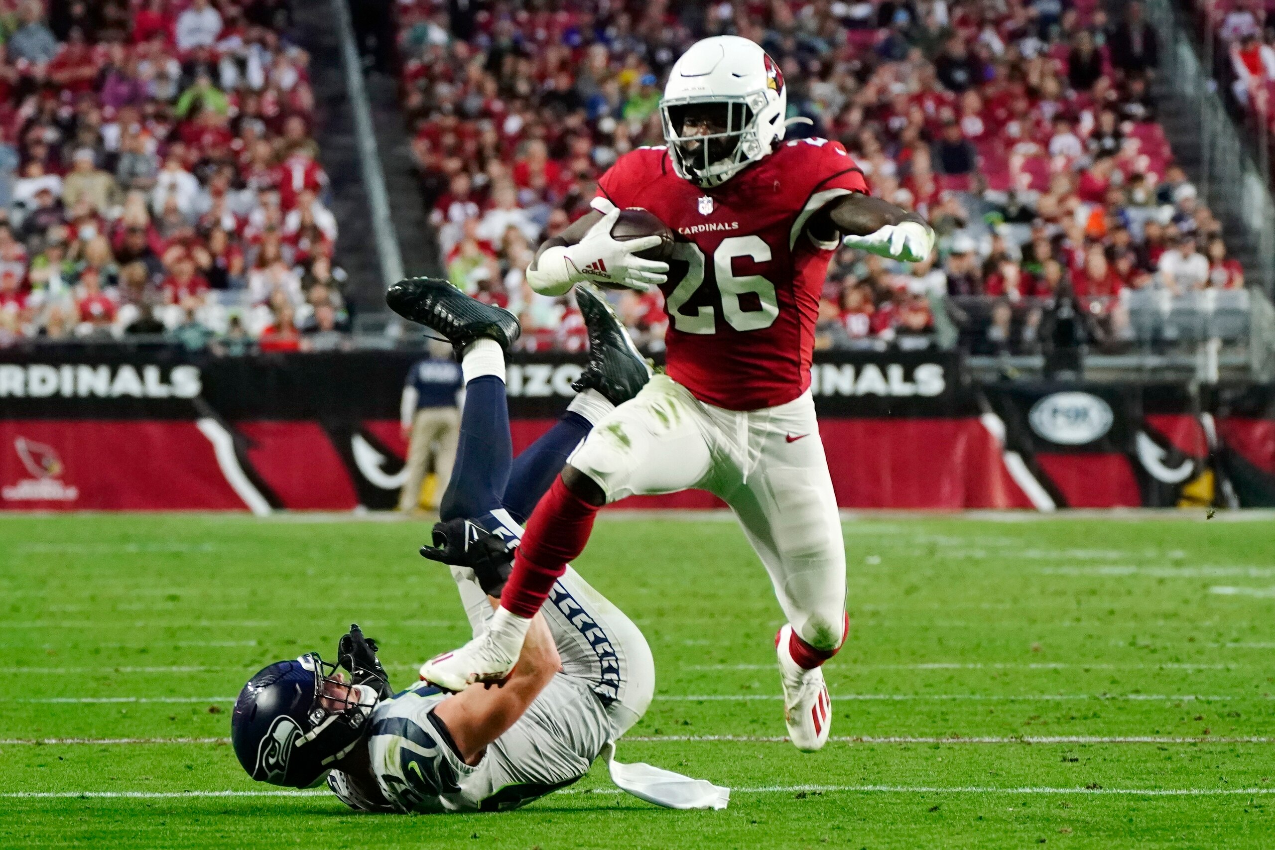 Arizona Cardinals running back Eno Benjamin (26) leaps over Seattle Seahawks linebacker Cody Barton, left, during the second half of an NFL football game Sunday, Jan. 9, 2022, in Glendale, Ariz. The Seahawks won 38-30. (AP Photo/Darryl Webb)