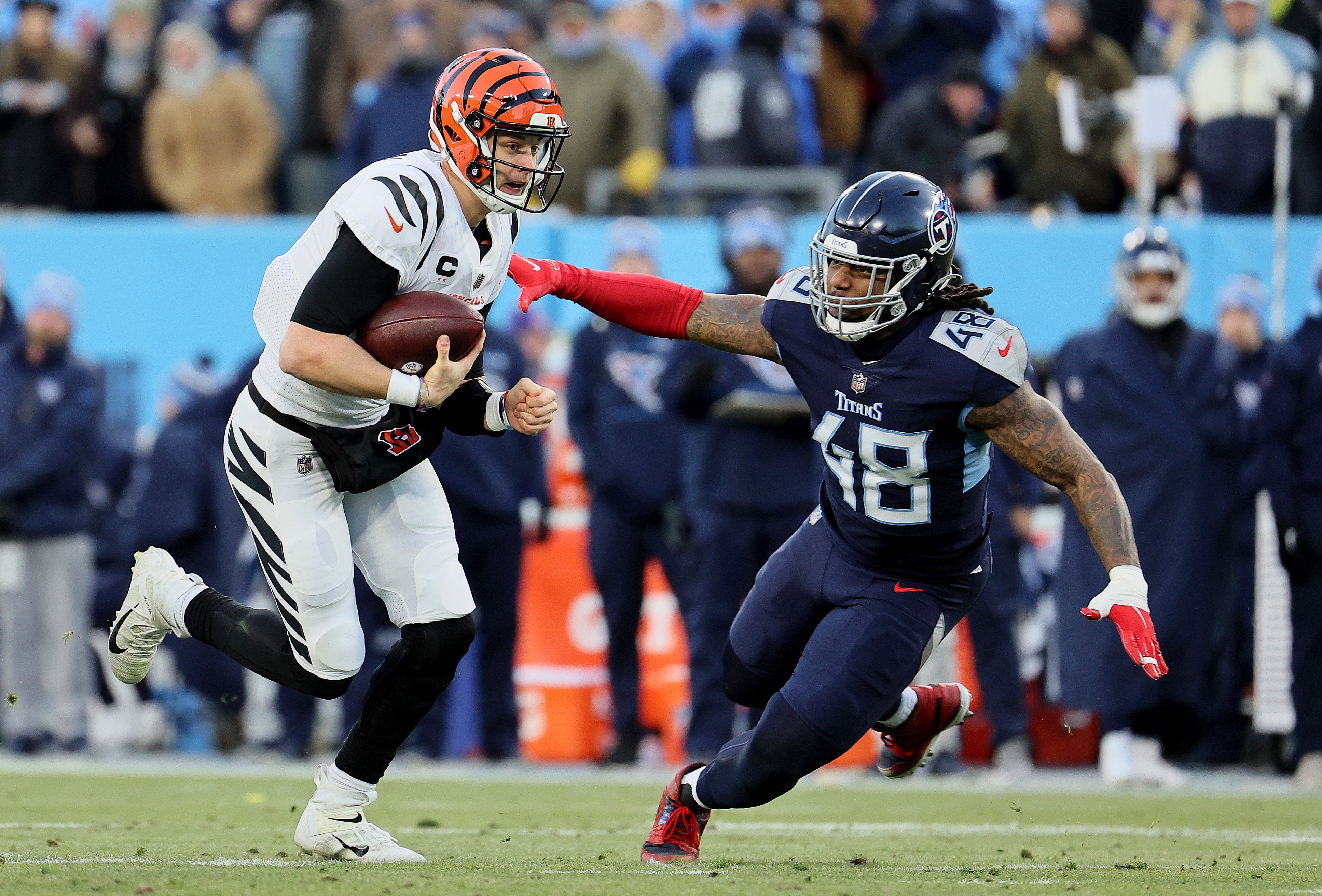 NASHVILLE, TENNESSEE - JANUARY 22: Quarterback Joe Burrow #9 of the Cincinnati Bengals is tackled by outside linebacker Bud Dupree #48 of the Tennessee Titans during the second quarter in the AFC Divisional Playoff game at Nissan Stadium on January 22, 2022 in Nashville, Tennessee. (Photo by Andy Lyons/Getty Images)