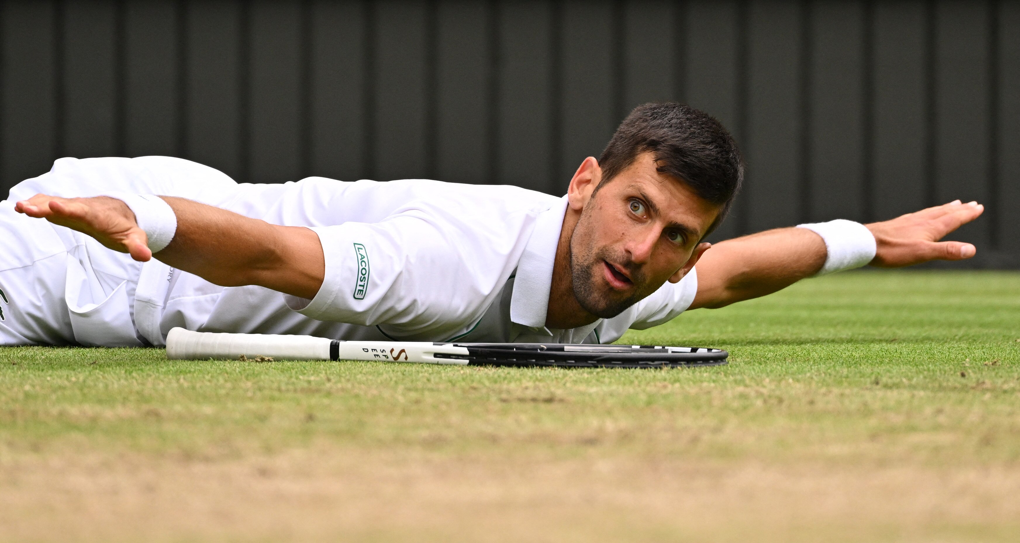 Serbia's Novak Djokovic reacts as he lies on the court during his men's singles quarter final tennis match against Italy's Jannik Sinner on the ninth day of the 2022 Wimbledon Championships at The All England Tennis Club in Wimbledon, southwest London, on July 5, 2022. - RESTRICTED TO EDITORIAL USE (Photo by SEBASTIEN BOZON / AFP) / RESTRICTED TO EDITORIAL USE (Photo by SEBASTIEN BOZON/AFP via Getty Images)