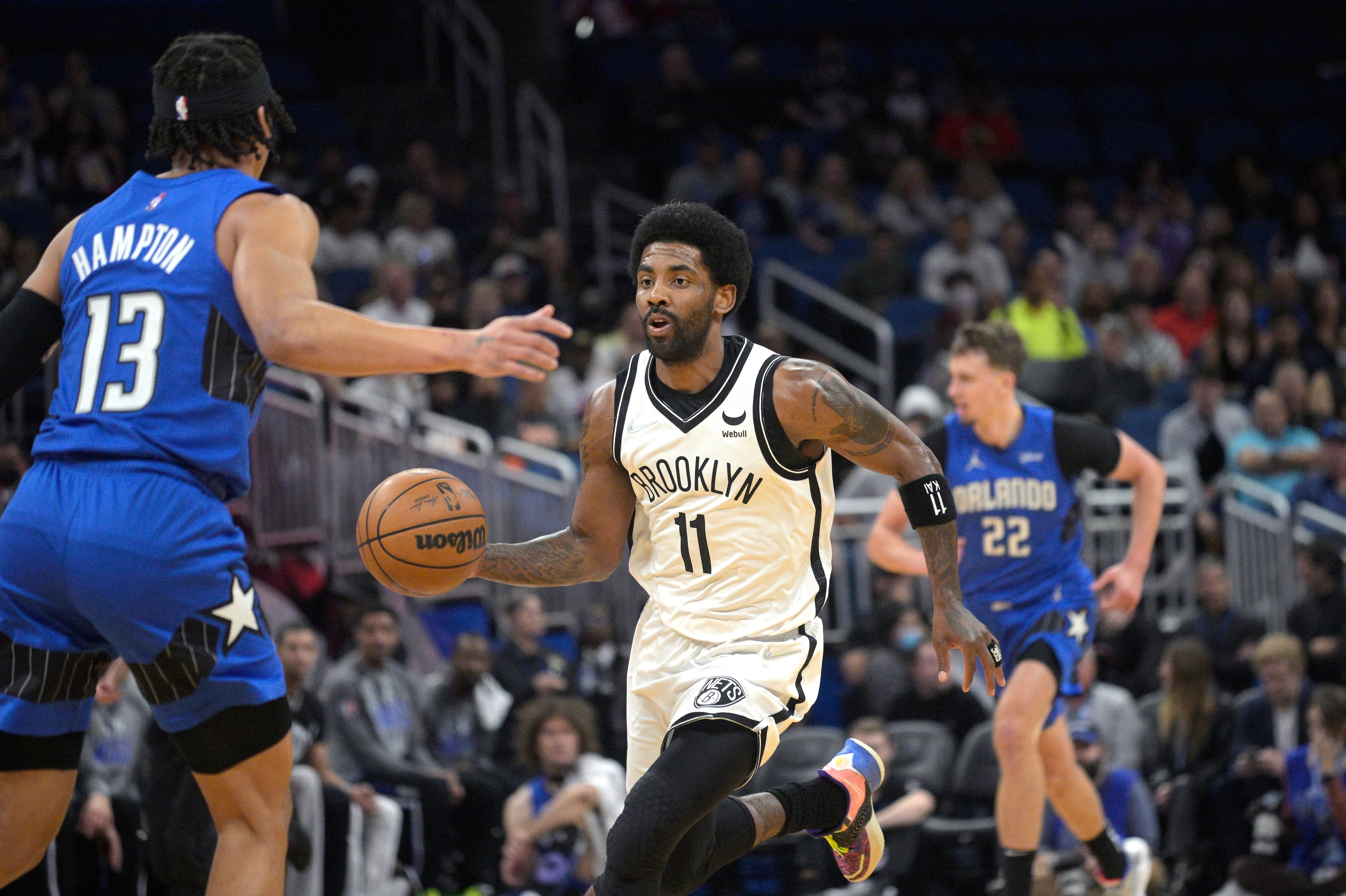 Brooklyn Nets guard Kyrie Irving (11) drives to the basket in front of Orlando Magic guard R.J. Hampton (13) during the first half of an NBA basketball game, Tuesday, March 15, 2022, in Orlando, Fla. (AP Photo/Phelan M. Ebenhack)