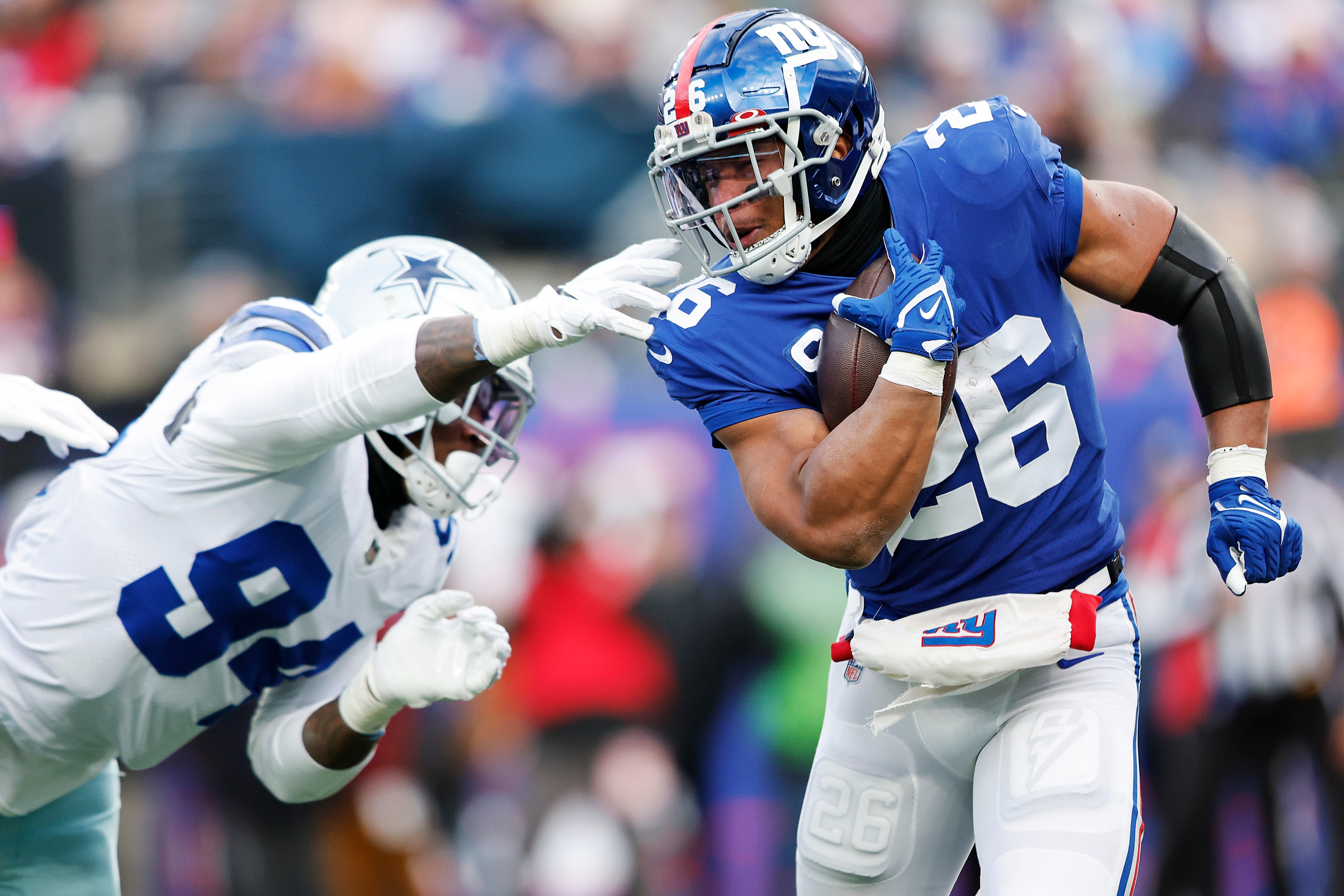 EAST RUTHERFORD, NEW JERSEY - DECEMBER 19: Saquon Barkley #26 of the New York Giants runs the ball and looks to avoid a tackle by Randy Gregory #94 of the Dallas Cowboys during the third quarter at MetLife Stadium on December 19, 2021 in East Rutherford, New Jersey. (Photo by Rey Del Rio/Getty Images)