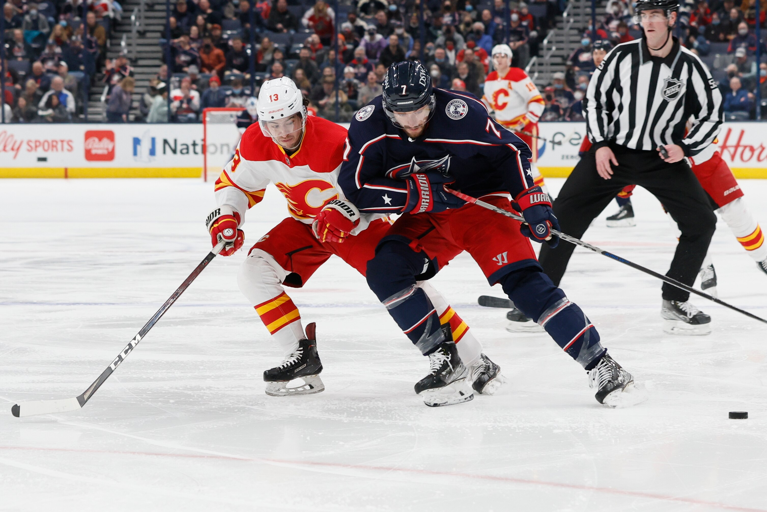 Columbus Blue Jackets' Sean Kuraly, right, carries the puck across the blue line against Calgary Flames' Johnny Gaudreau during the second period of an NHL hockey game Wednesday, Jan. 26, 2022, in Columbus, Ohio. (AP Photo/Jay LaPrete)