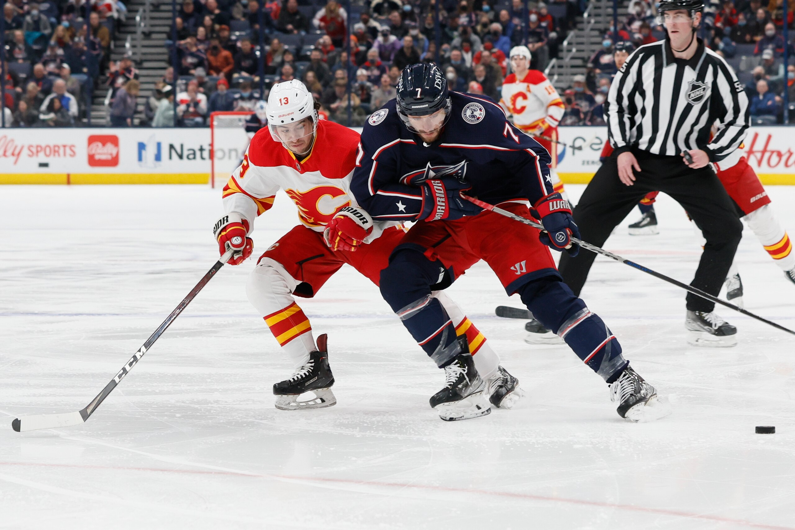 Columbus Blue Jackets' Sean Kuraly, right, carries the puck across the blue line against Calgary Flames' Johnny Gaudreau during the second period of an NHL hockey game Wednesday, Jan. 26, 2022, in Columbus, Ohio. (AP Photo/Jay LaPrete)