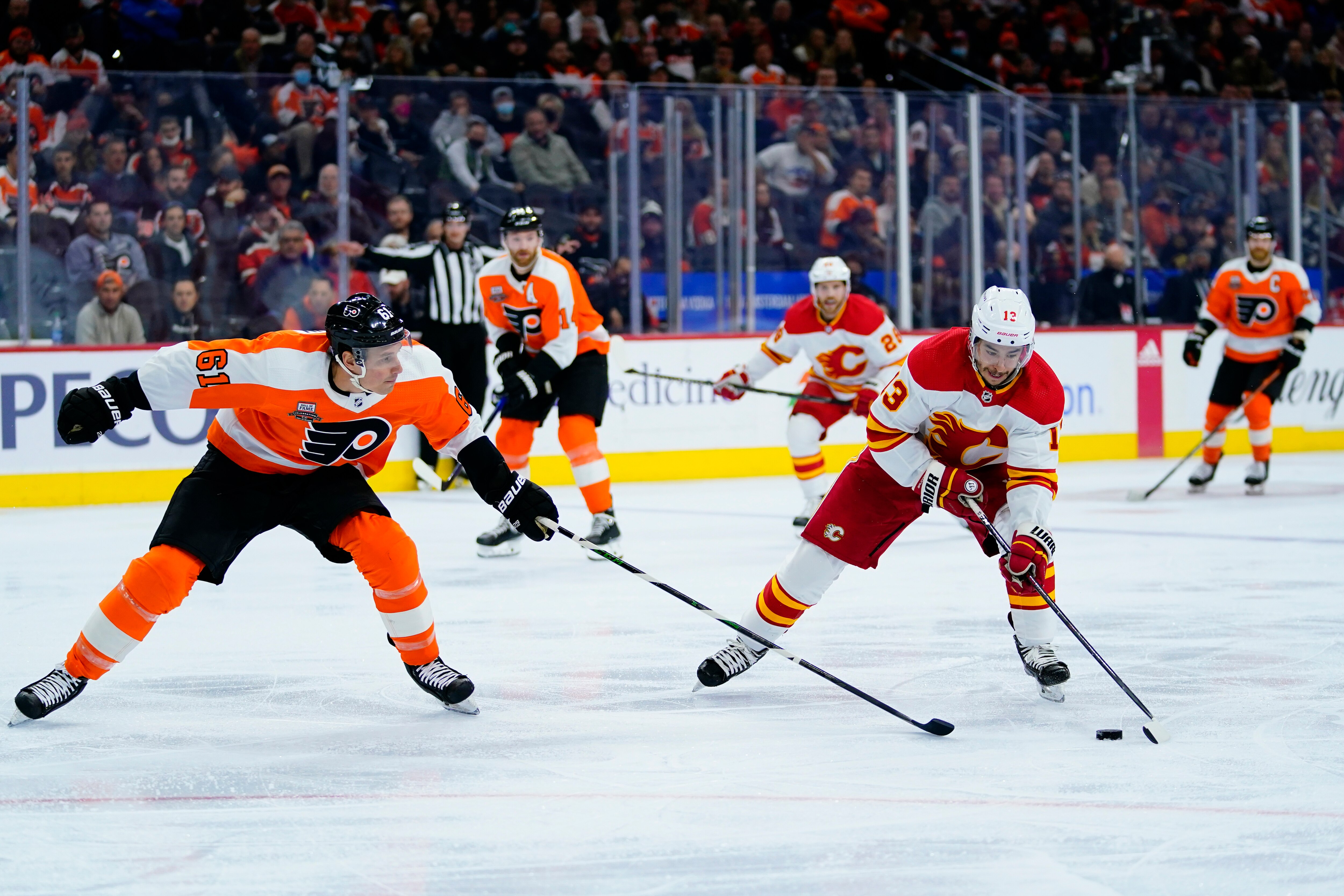 Calgary Flames' Johnny Gaudreau (13) tries to get past Philadelphia Flyers' Justin Braun (61) during the first period of an NHL hockey game, Tuesday, Nov. 16, 2021, in Philadelphia. (AP Photo/Matt Slocum)