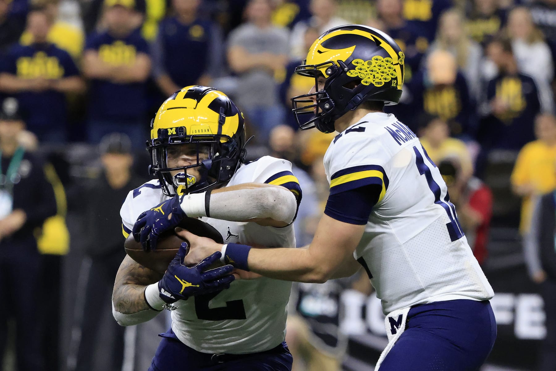 INDIANAPOLIS, INDIANA - DECEMBER 04: Cade McNamara #12 of the Michigan Wolverines hands the ball off to Blake Corum #2 of the Michigan Wolverines during the Big Ten Football Championship against the Iowa Hawkeyes at Lucas Oil Stadium on December 04, 2021 in Indianapolis, Indiana. (Photo by Justin Casterline/Getty Images)