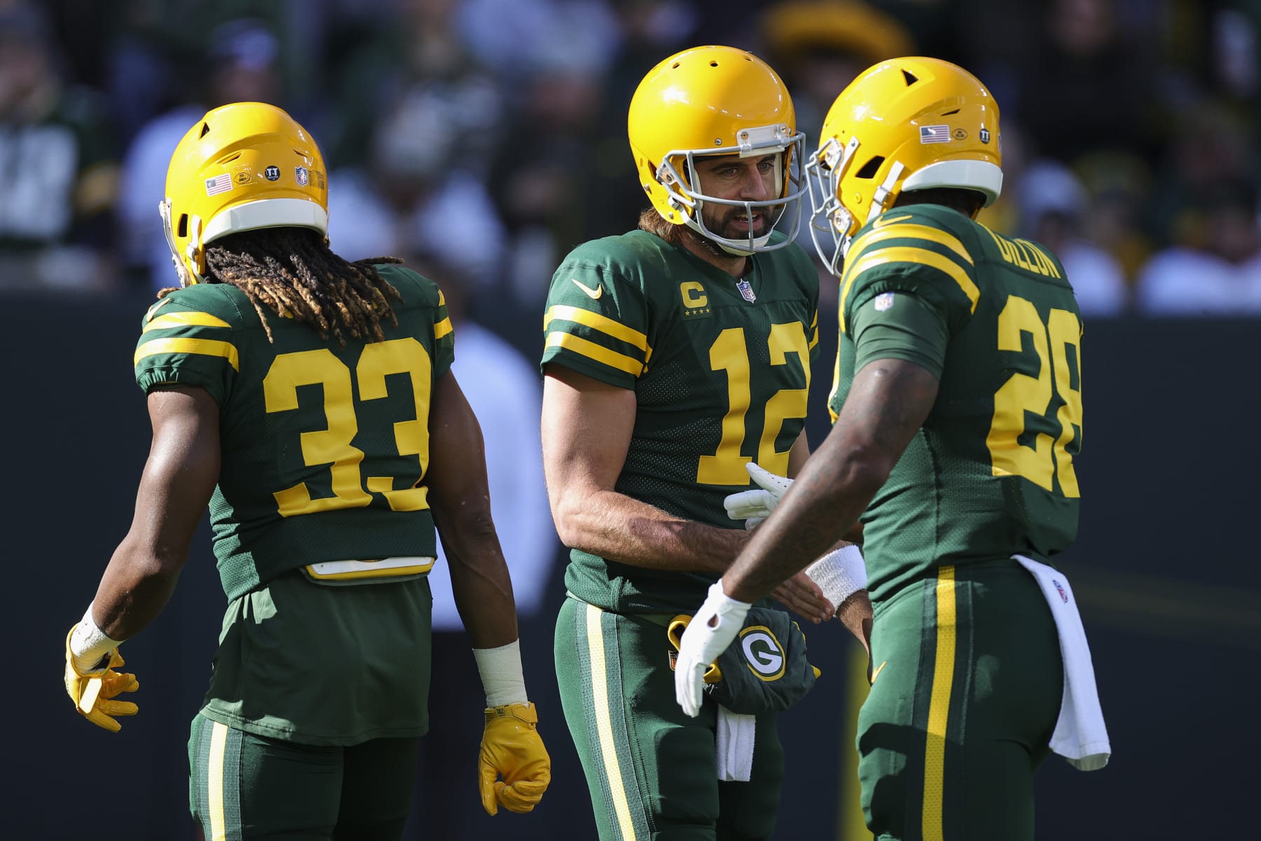 GREEN BAY, WISCONSIN - OCTOBER 24: Aaron Jones #33, Aaron Rodgers #12, and AJ Dillon #28 of the Green Bay Packers meet before the game against the Washington Football Team at Lambeau Field on October 24, 2021 in Green Bay, Wisconsin. (Photo by Stacy Revere/Getty Images)