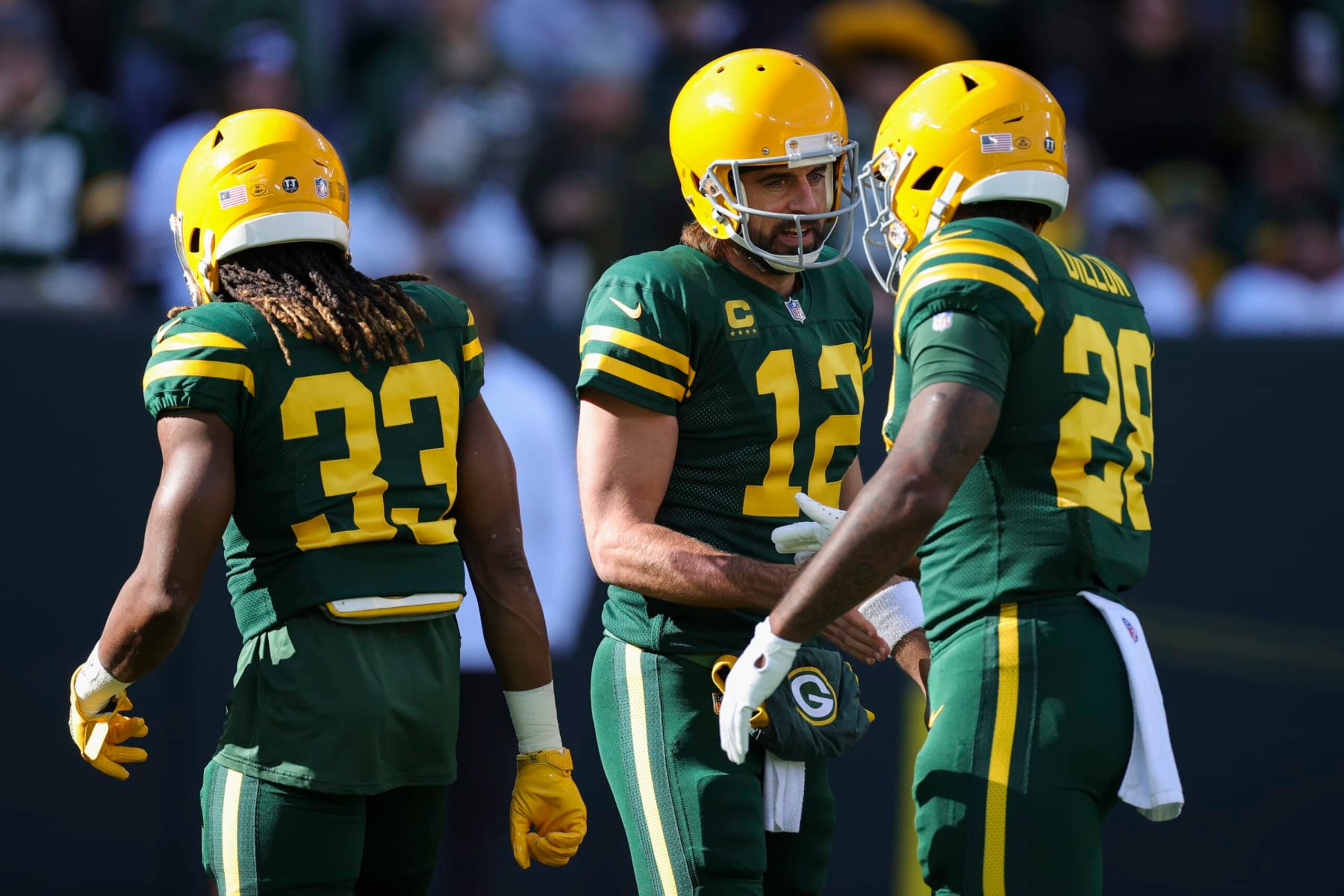 GREEN BAY, WISCONSIN - OCTOBER 24: Aaron Jones #33, Aaron Rodgers #12, and AJ Dillon #28 of the Green Bay Packers meet before the game against the Washington Football Team at Lambeau Field on October 24, 2021 in Green Bay, Wisconsin. (Photo by Stacy Revere/Getty Images)