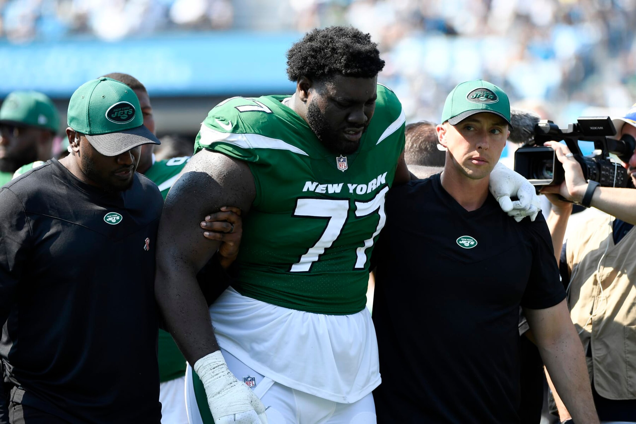 CHARLOTTE, NORTH CAROLINA - SEPTEMBER 12: Mekhi Becton #77 of the New York Jets is helped off the field after being injured during the third quarter against the Carolina Panthers at Bank of America Stadium on September 12, 2021 in Charlotte, North Carolina. (Photo by Mike Comer/Getty Images)