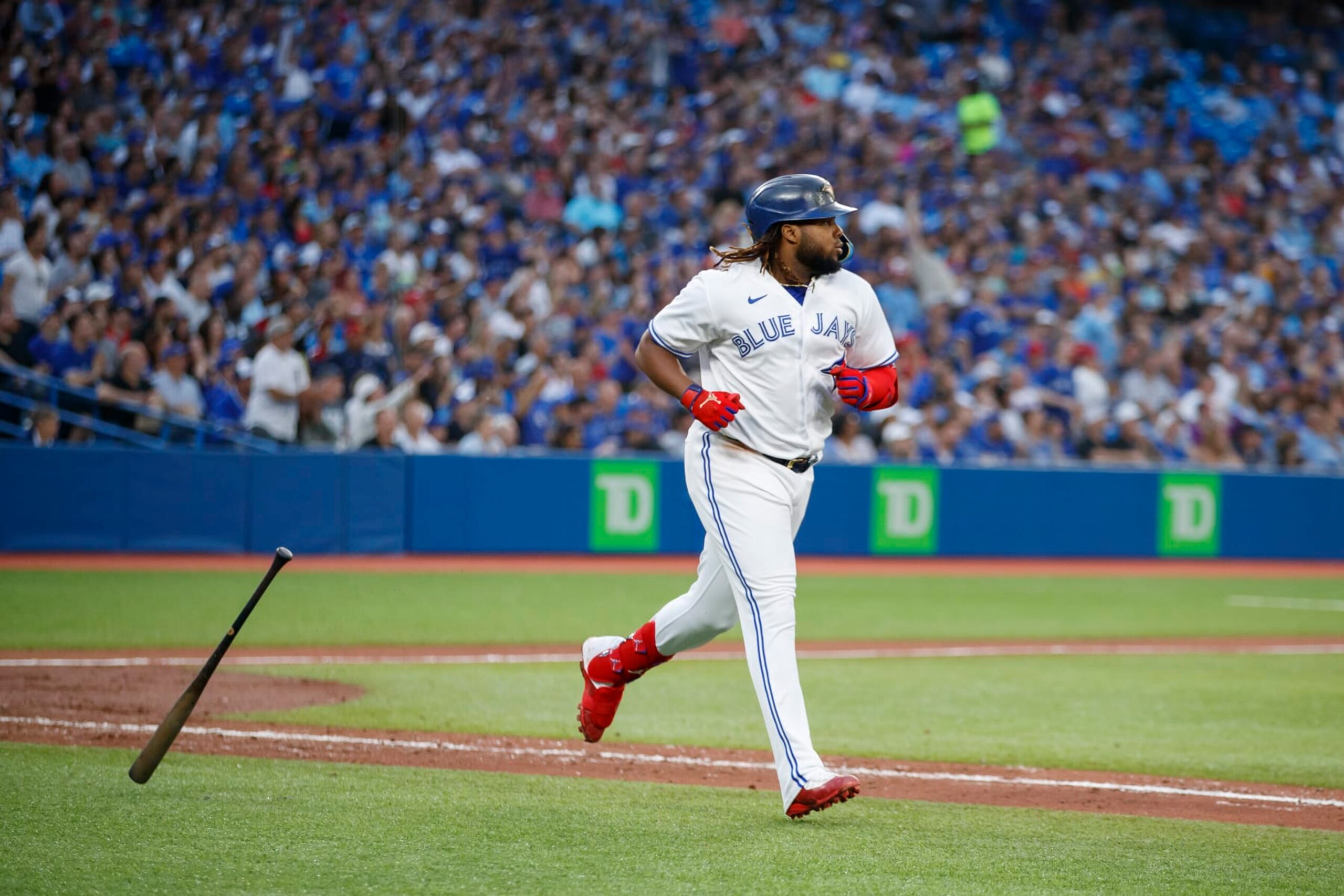 TORONTO, ON - JULY 13: Vladimir Guerrero Jr. #27 of the Toronto Blue Jays hits a sacrifice fly to allow George Springer #4 to score in the fifth inning of their MLB game against the Philadelphia Phillies at Rogers Centre on July 13, 2022 in Toronto, Canada. (Photo by Cole Burston/Getty Images)