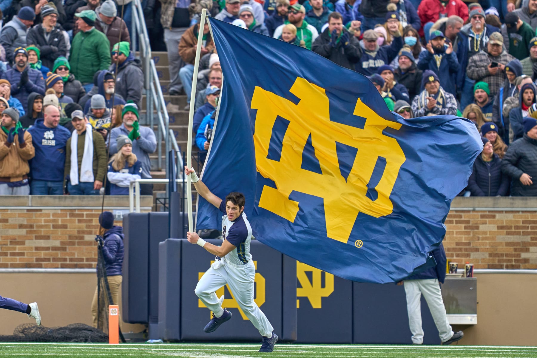 SOUTH BEND, IN - NOVEMBER 20: A Notre Dame Fighting Irish cheerleader runs onto the field with a Notre Dame Fighting Irish flag after a touchdown play during a game between the Notre Dame Fighting Irish and the Georgia Tech Yellow Jackets on November 20, 2021 at Notre Dame Stadium, in South Bend, IN.  (Photo by Robin Alam/Icon Sportswire via Getty Images)