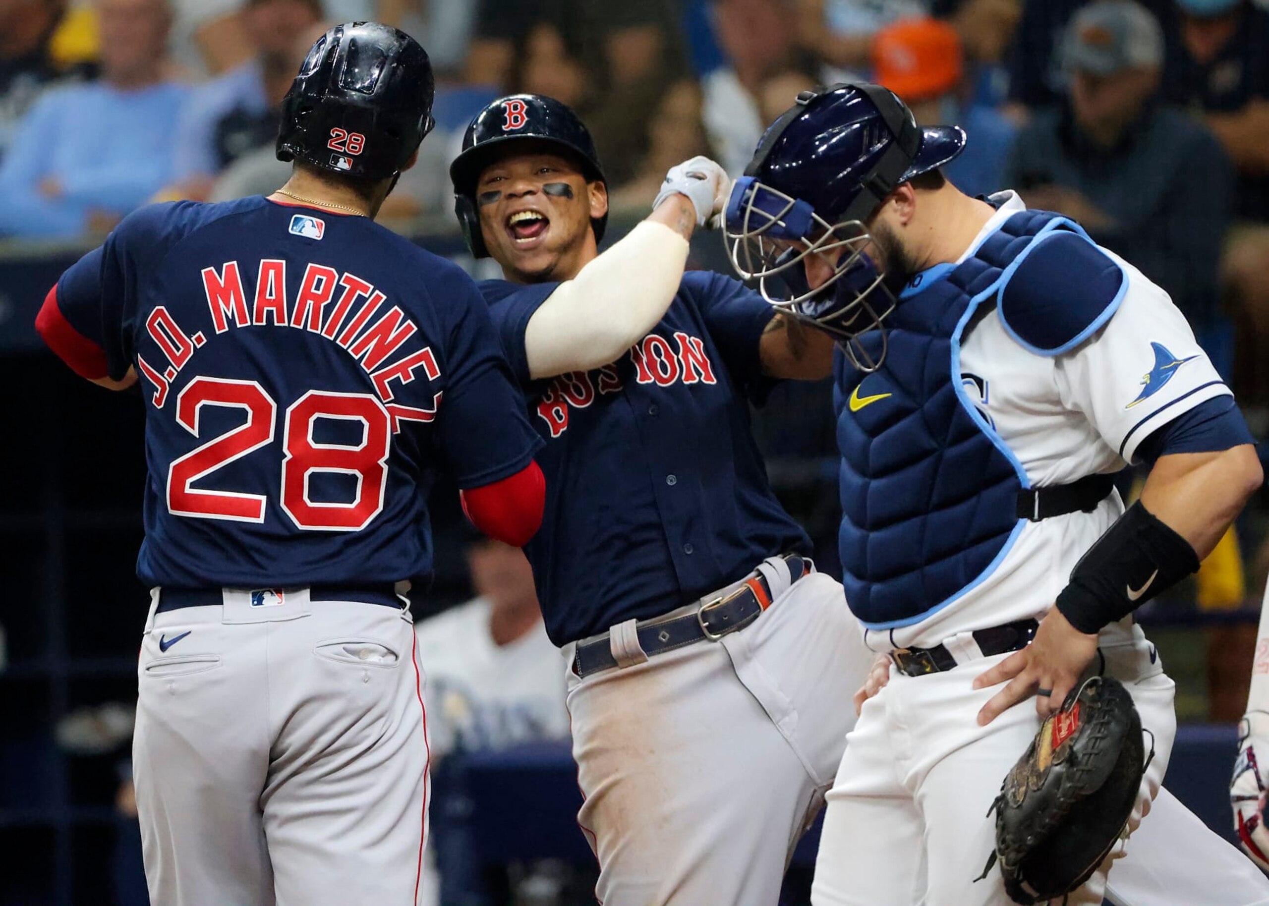 St. Petersburg - October 8: Boston Red Sox left fielder J.D. Martinez (28) at home plate celebrating with teammate Rafael Devers after hitting a go ahead 3 run home run in front of Tampa Bay Rays catcher Mike Zunino (10) during fifth inning action. The Boston Red Sox visit the Tampa Bay Rays for Game 2 of the MLB American League Division Series (ALDS) playoff at Tropicana Field in St. Petersburg, FL on Oct. 8, 2021. (Photo by Matthew J. Lee/The Boston Globe via Getty Images)
