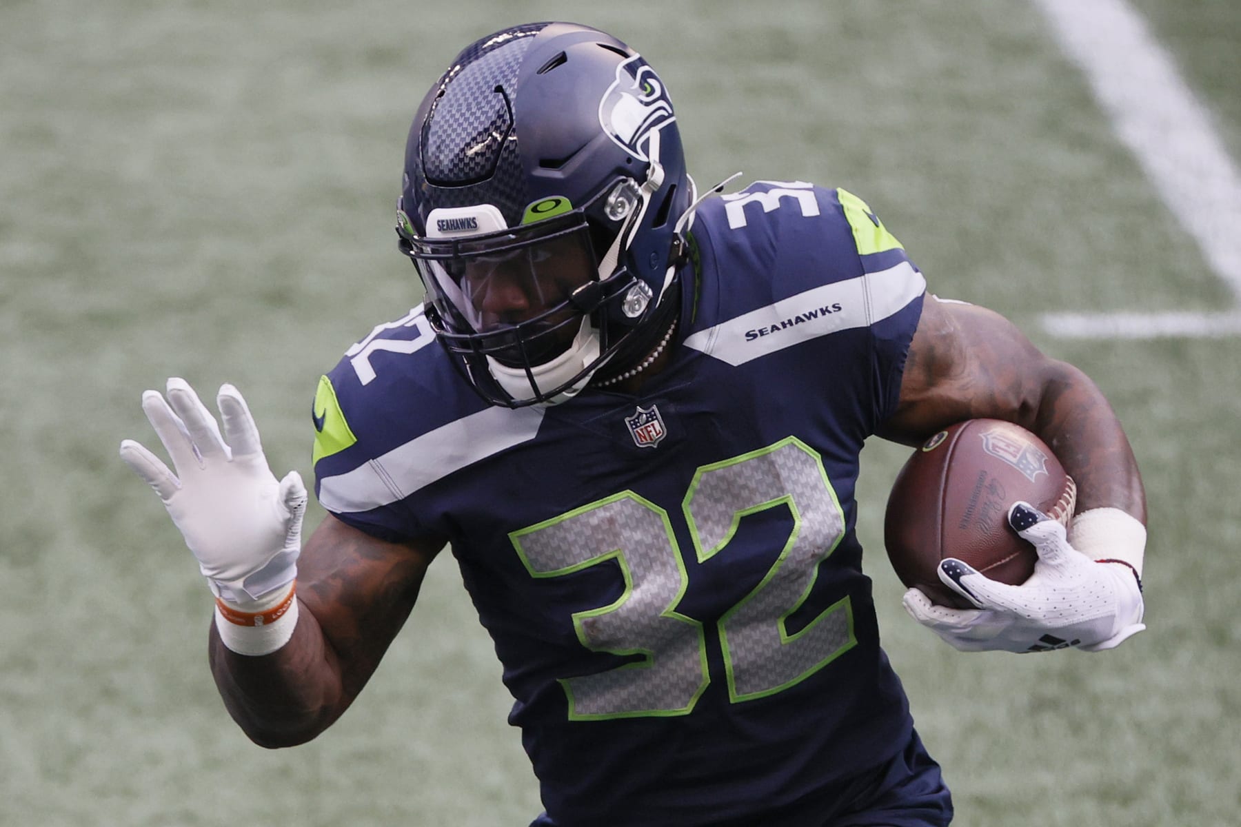 SEATTLE, WASHINGTON - JANUARY 09: Running back Chris Carson #32 of the Seattle Seahawks carries the football against the defense of the Los Angeles Rams during the first quarter of the NFC Wild Card Playoff game at Lumen Field on January 09, 2021 in Seattle, Washington. (Photo by Steph Chambers/Getty Images)