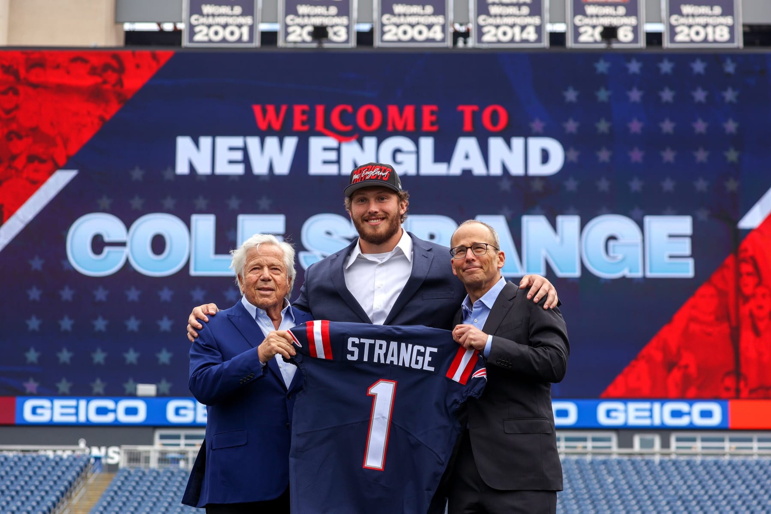 Foxborough, MA - April 29: New England Patriots first-round draft pick Cole Strange pictured with Robert and Jonathan Kraft for the presentation of a ceremonial #1 jersey on the game field at Gillette Stadium in Foxborough, MA on April 29, 2022. (Photo by Barry Chin/The Boston Globe via Getty Images)