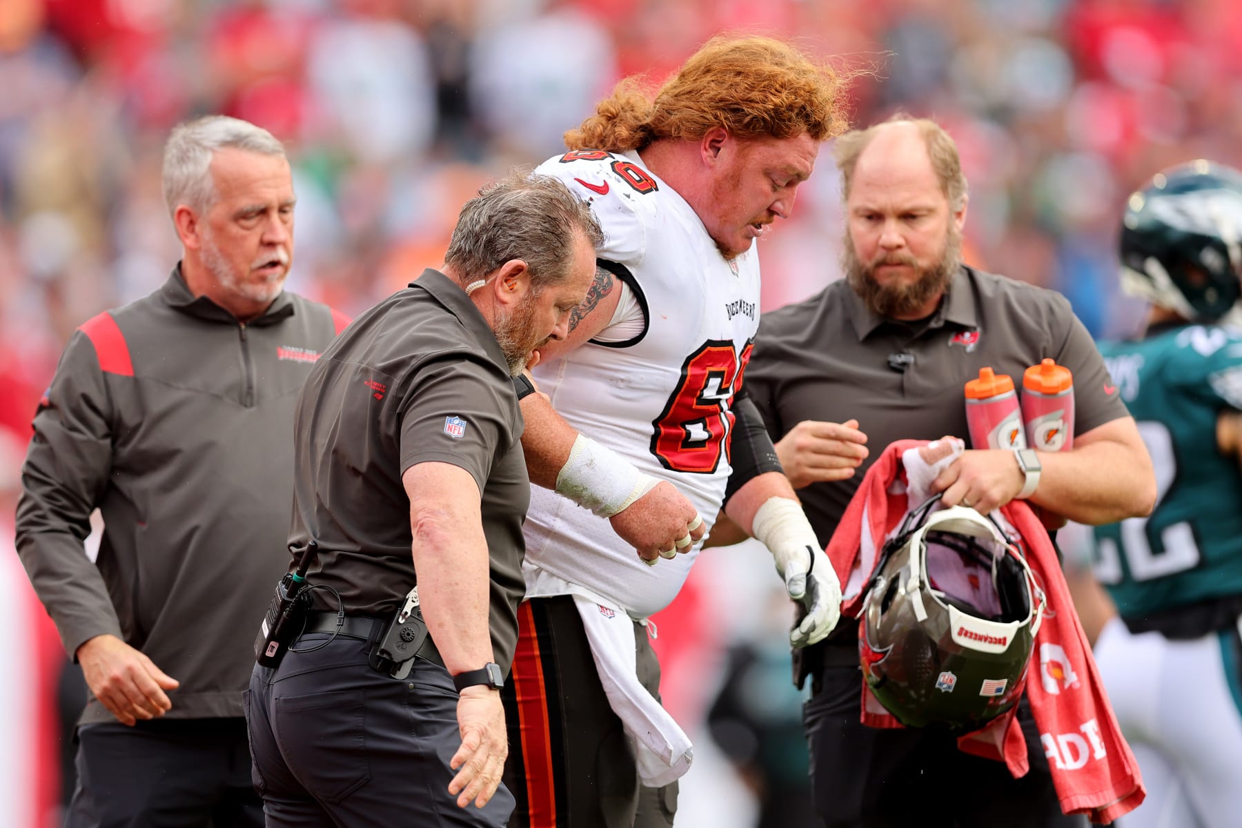 TAMPA, FLORIDA - JANUARY 16: Ryan Jensen #66 of the Tampa Bay Buccaneers is helped off the field after a play against the Philadelphia Eagles during the first quarter in the NFC Wild Card Playoff game at Raymond James Stadium on January 16, 2022 in Tampa, Florida. (Photo by Michael Reaves/Getty Images)