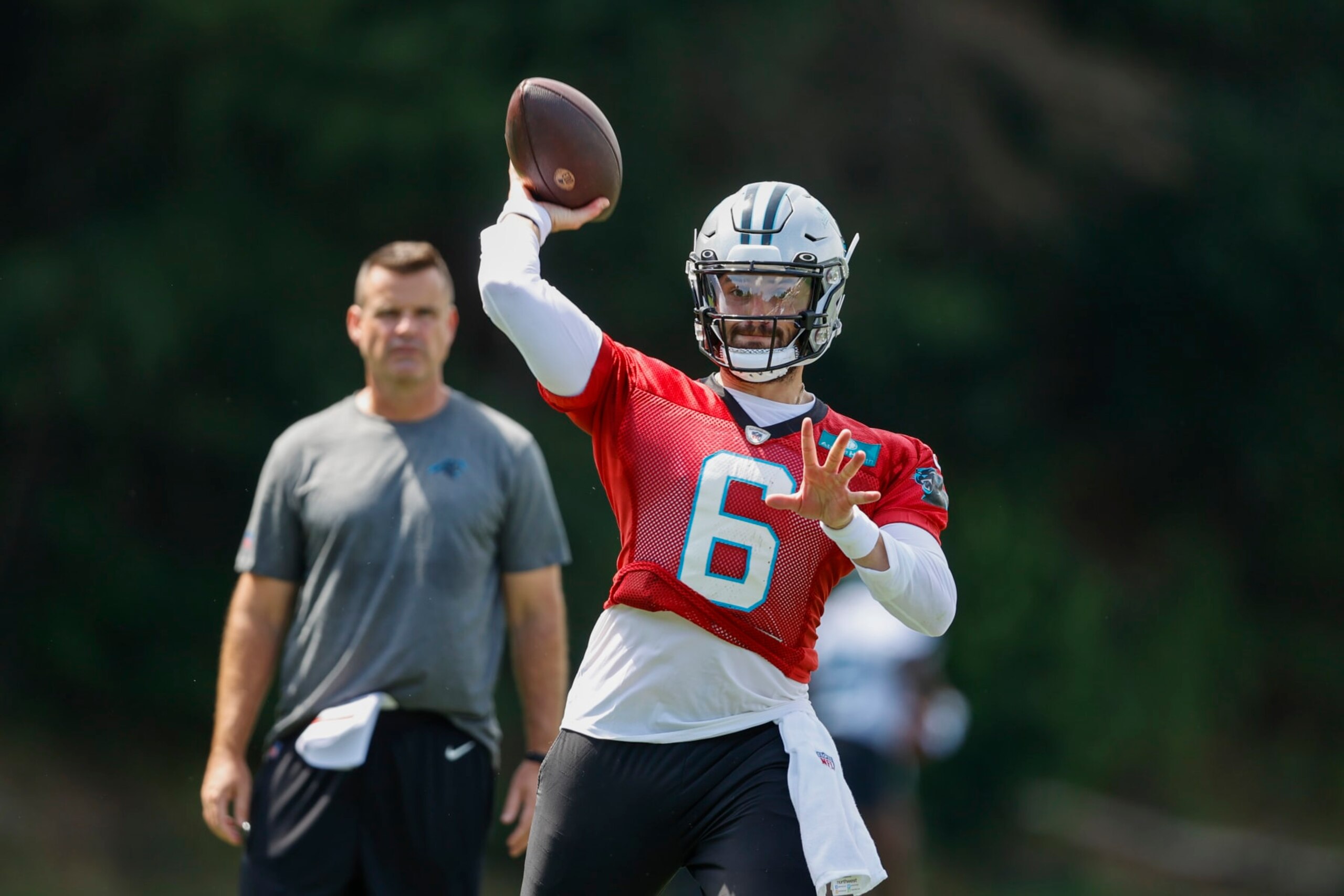 Carolina Panthers quarterback Baker Mayfield throws a pass as quarterbacks coach Sean Ryan looks on at the NFL football team's training camp at Wofford College in Spartanburg, S.C., Wednesday, July 27, 2022. (AP Photo/Nell Redmond)