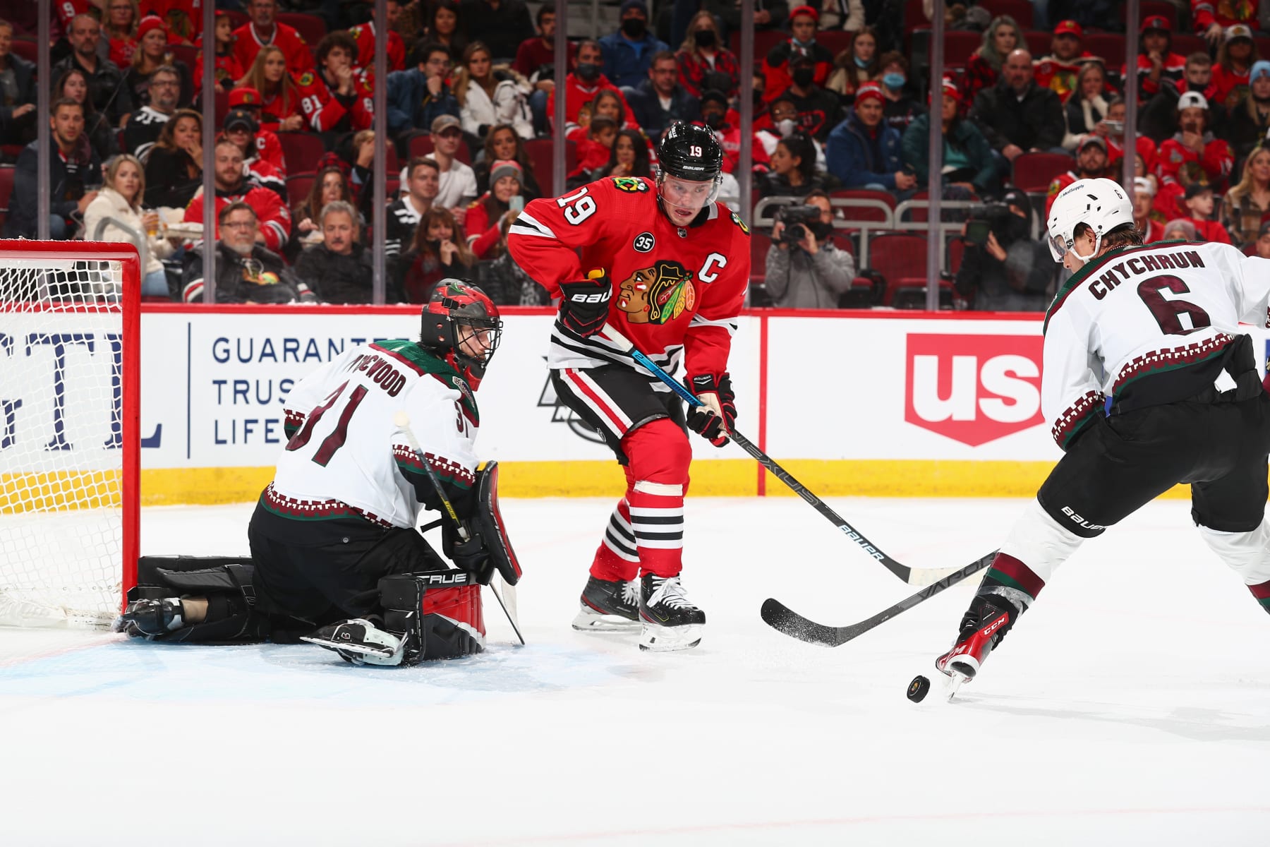 CHICAGO, ILLINOIS - NOVEMBER 12: Jakob Chychrun #6 of the Arizona Coyotes approaches the puck as Jonathan Toews #19 of the Chicago Blackhawks and goalie Scott Wedgewood #31 of the Arizona Coyotes watch in the second period at United Center on November 12, 2021 in Chicago, Illinois. (Photo by Chase Agnello-Dean/NHLI via Getty Images)