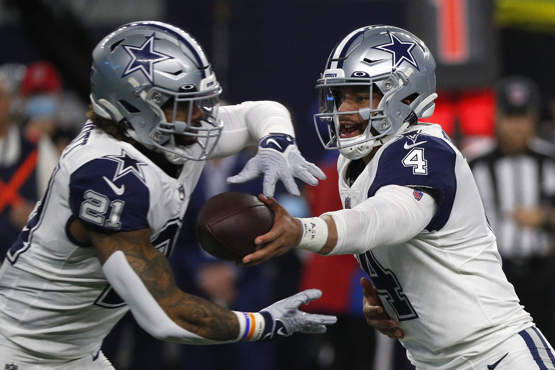 ARLINGTON, TEXAS - JANUARY 02: Ezekiel Elliott #21 of the Dallas Cowboys takes the handoff from Dak Prescott #4 of the Dallas Cowboys during the game against the Arizona Cardinals at AT&T Stadium on January 02, 2022 in Arlington, Texas. (Photo by Richard Rodriguez/Getty Images)