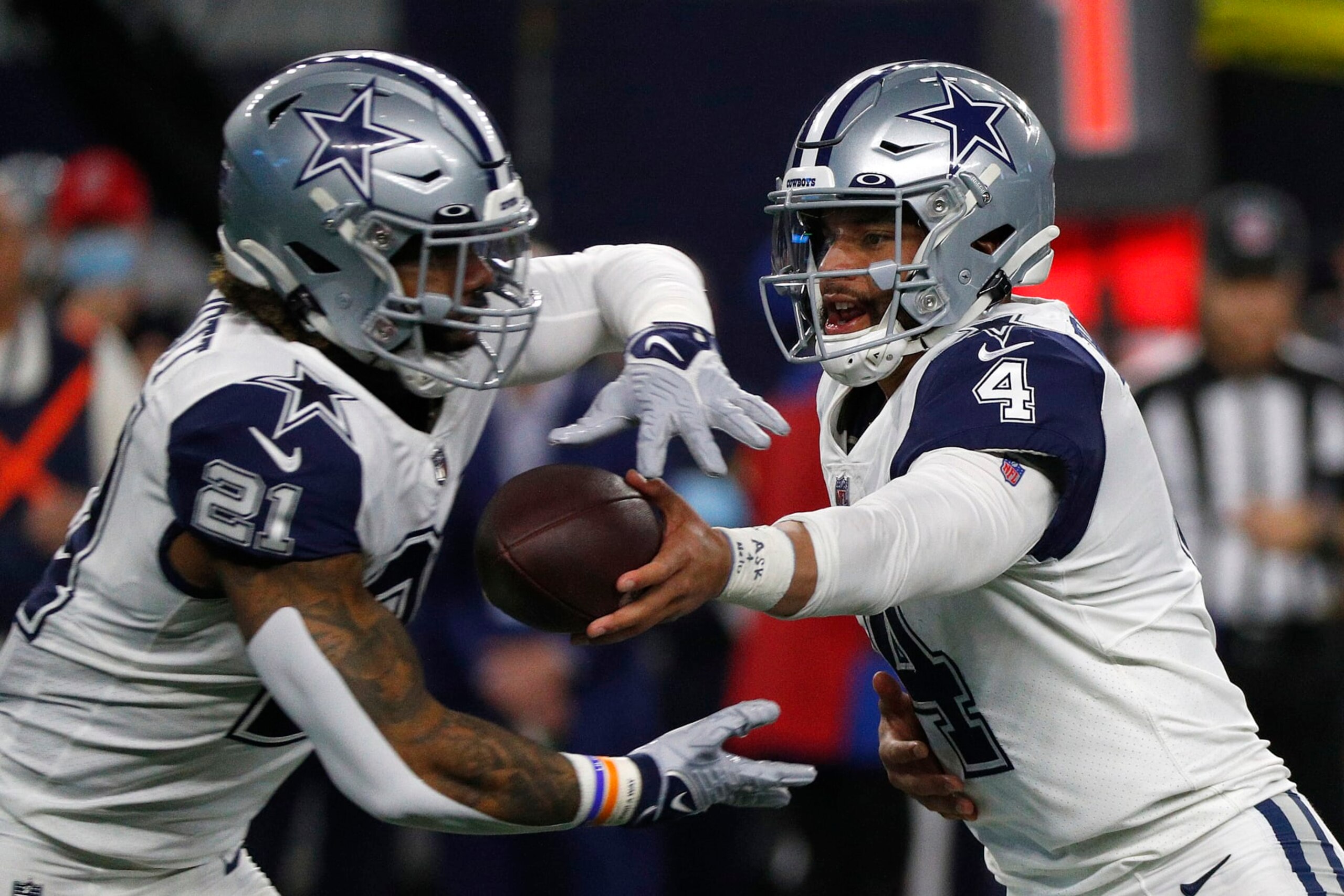 ARLINGTON, TEXAS - JANUARY 02: Ezekiel Elliott #21 of the Dallas Cowboys takes the handoff from Dak Prescott #4 of the Dallas Cowboys during the game against the Arizona Cardinals at AT&T Stadium on January 02, 2022 in Arlington, Texas. (Photo by Richard Rodriguez/Getty Images)
