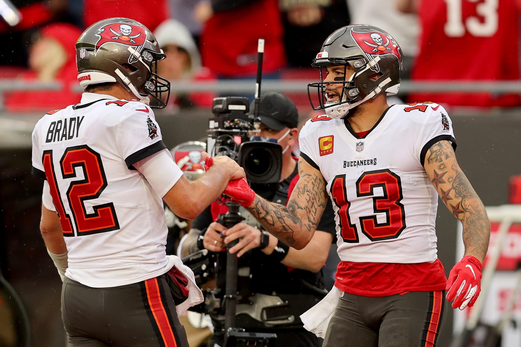 TAMPA, FLORIDA - JANUARY 16: Mike Evans #13 of the Tampa Bay Buccaneers celebrates with Tom Brady #12 after scoring a touchdown against the Philadelphia Eagles during the third quarter in the NFC Wild Card Playoff game at Raymond James Stadium on January 16, 2022 in Tampa, Florida. (Photo by Michael Reaves/Getty Images)