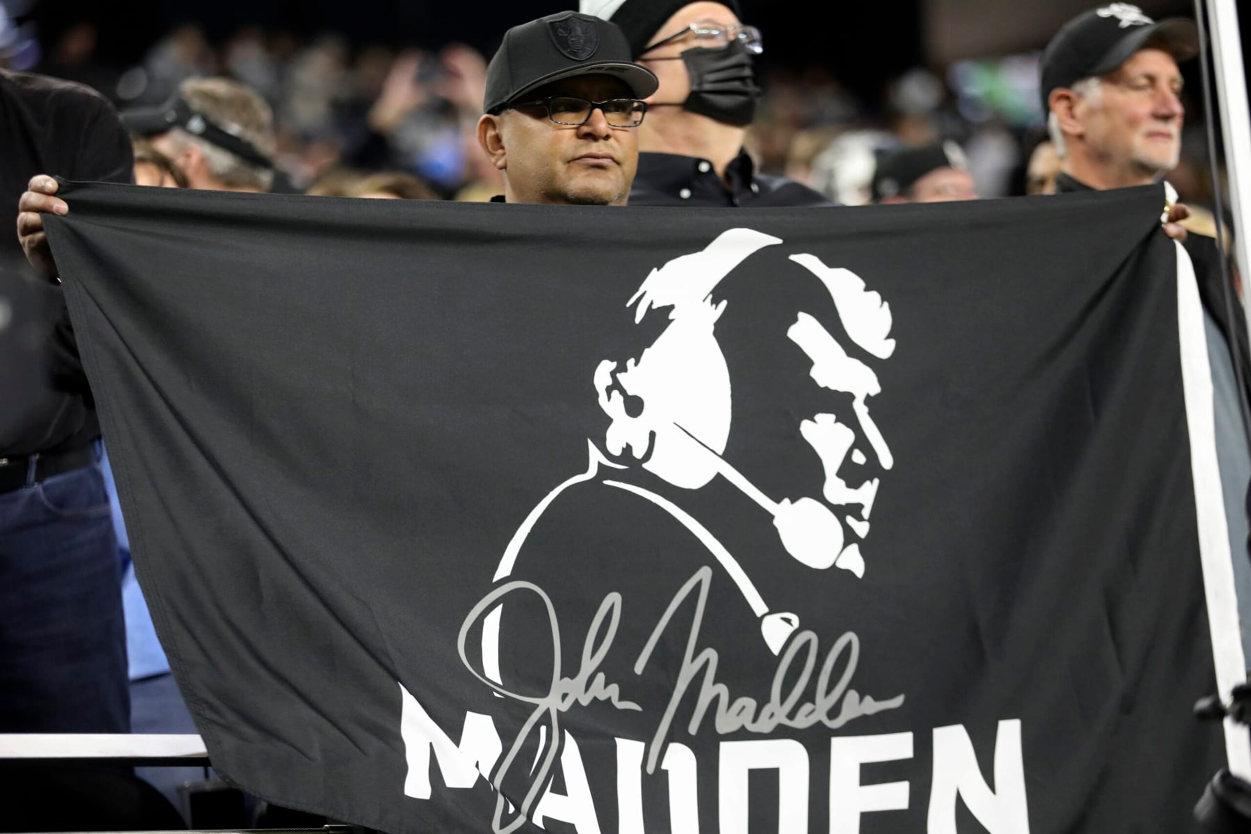 A Las Vegas Raiders fan holds a John Madden flag during the first half of an NFL football game, Sunday, Jan. 9, 2022, in Las Vegas. (AP Photo/Ellen Schmidt)
