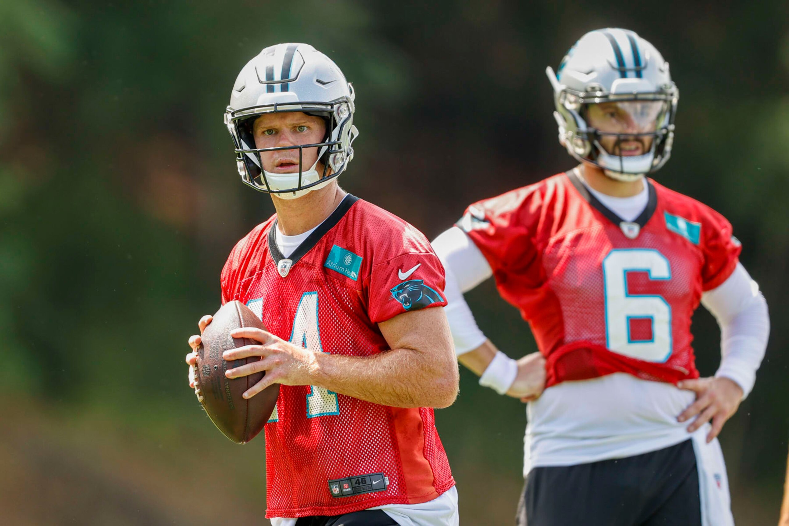 Carolina Panthers quarterback Sam Darnold, left, looks to throw as quarterback Baker Mayfield looks on during the NFL football team's training camp at Wofford College in Spartanburg, S.C., Wednesday, July 27, 2022. (AP Photo/Nell Redmond)