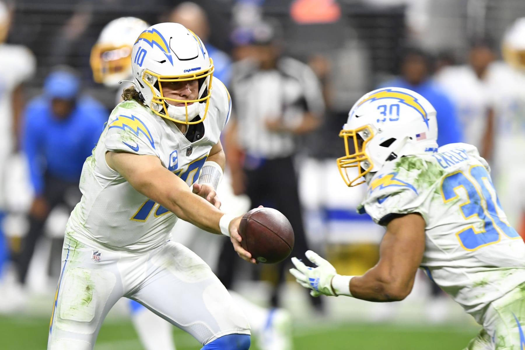 LAS VEGAS, NEVADA - JANUARY 09:  Quarterback Justin Herbert #10 hands the ball off to running back Austin Ekeler #30 of the Los Angeles Chargers during the second half of a game at Allegiant Stadium on January 09, 2022 in Las Vegas, Nevada. The Raiders defeated the Chargers 35-32 in overtime. (Photo by Chris Unger/Getty Images)